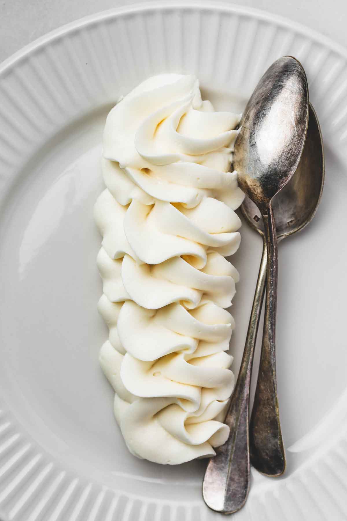 Vanilla buttercream piped into a tall swirl on a plate