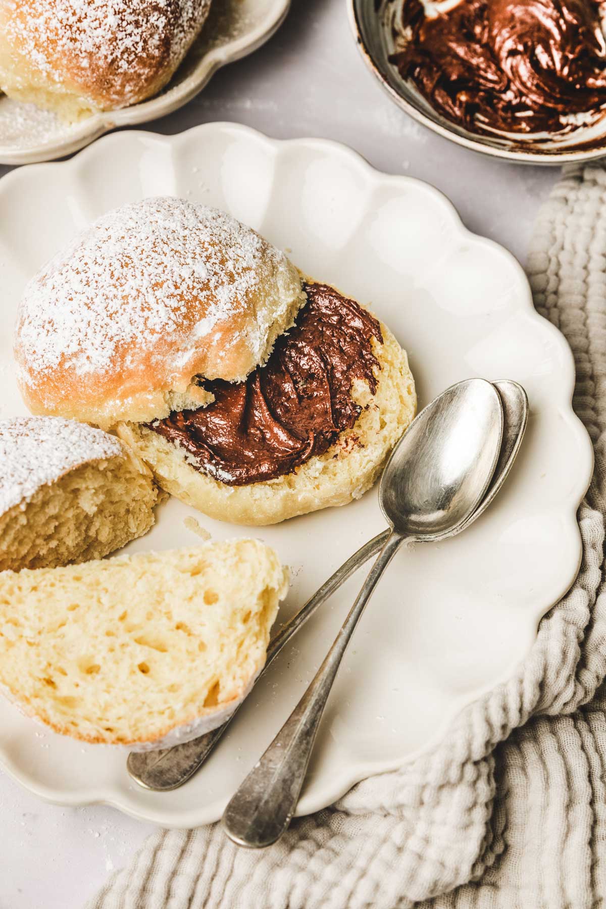 Sweet buns cut with chocolate spread on a plate with teaspoons