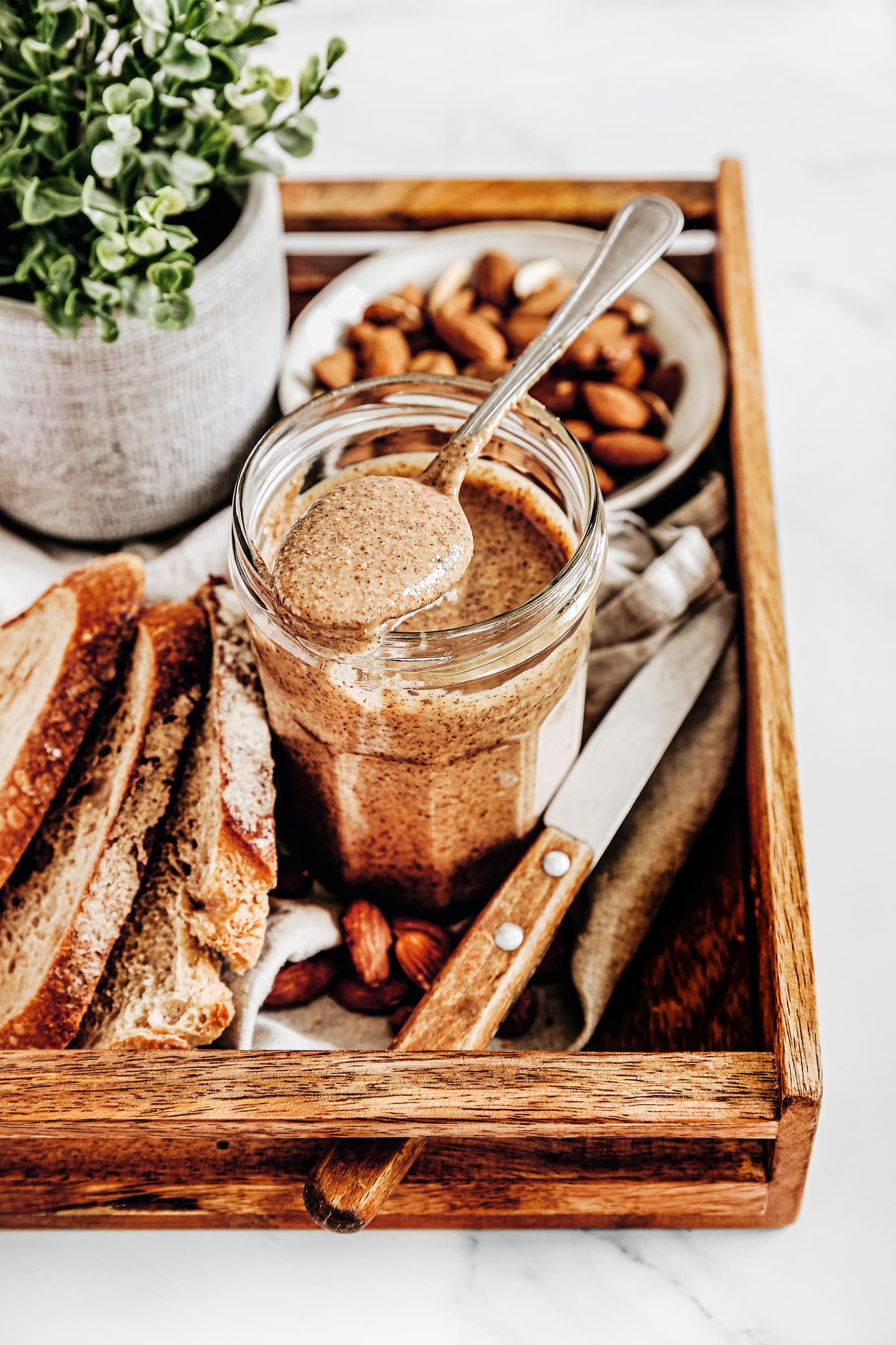 almond butter on a wood board with a teaspoon and bread