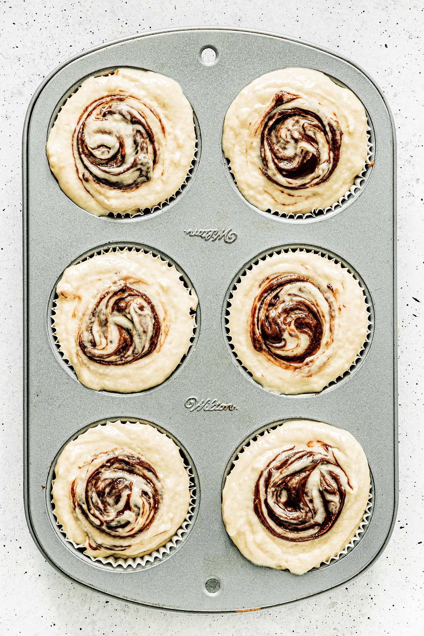 Muffin pan with nutella swirl muffins before baking