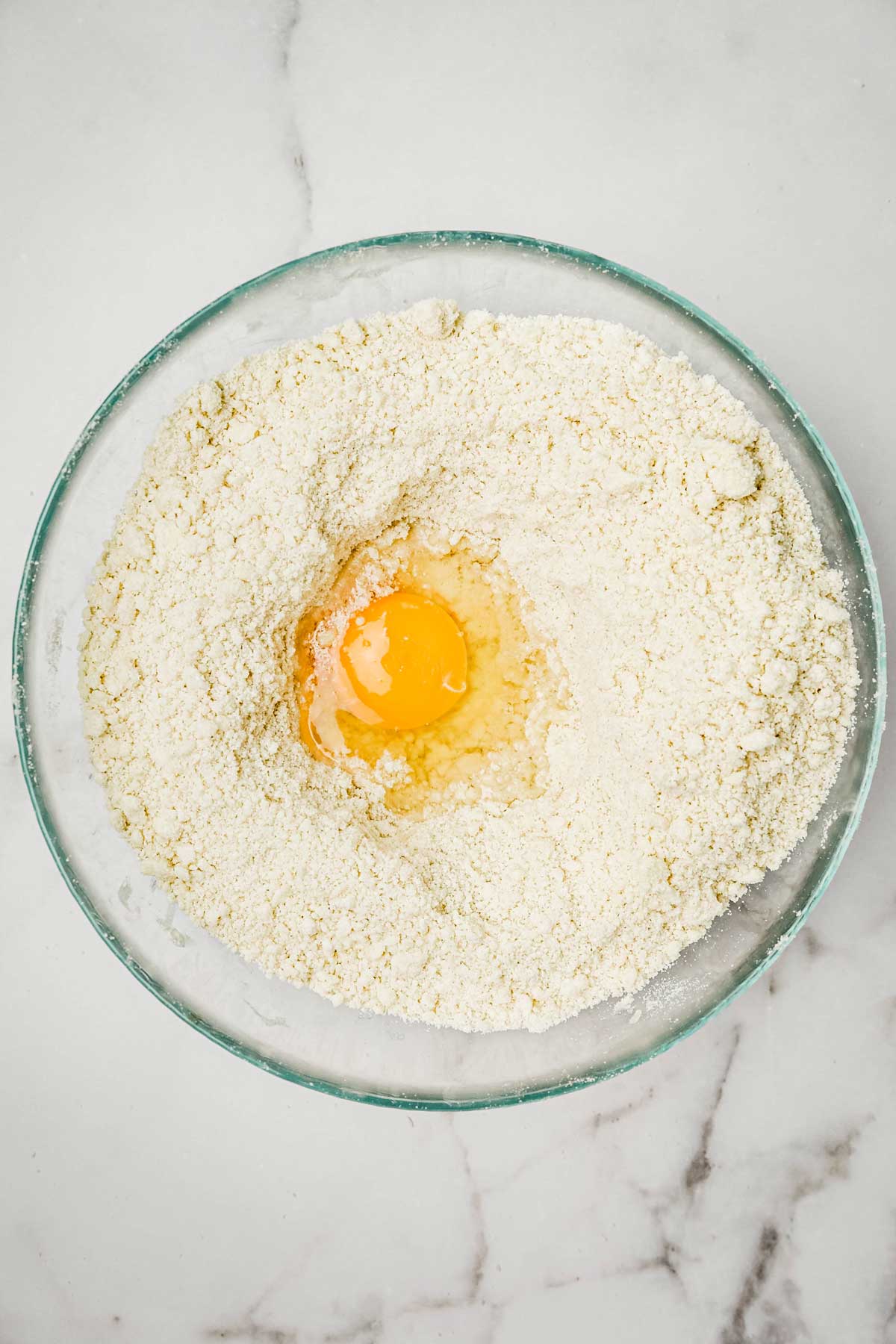 Medium bowl with dry ingredients and an egg