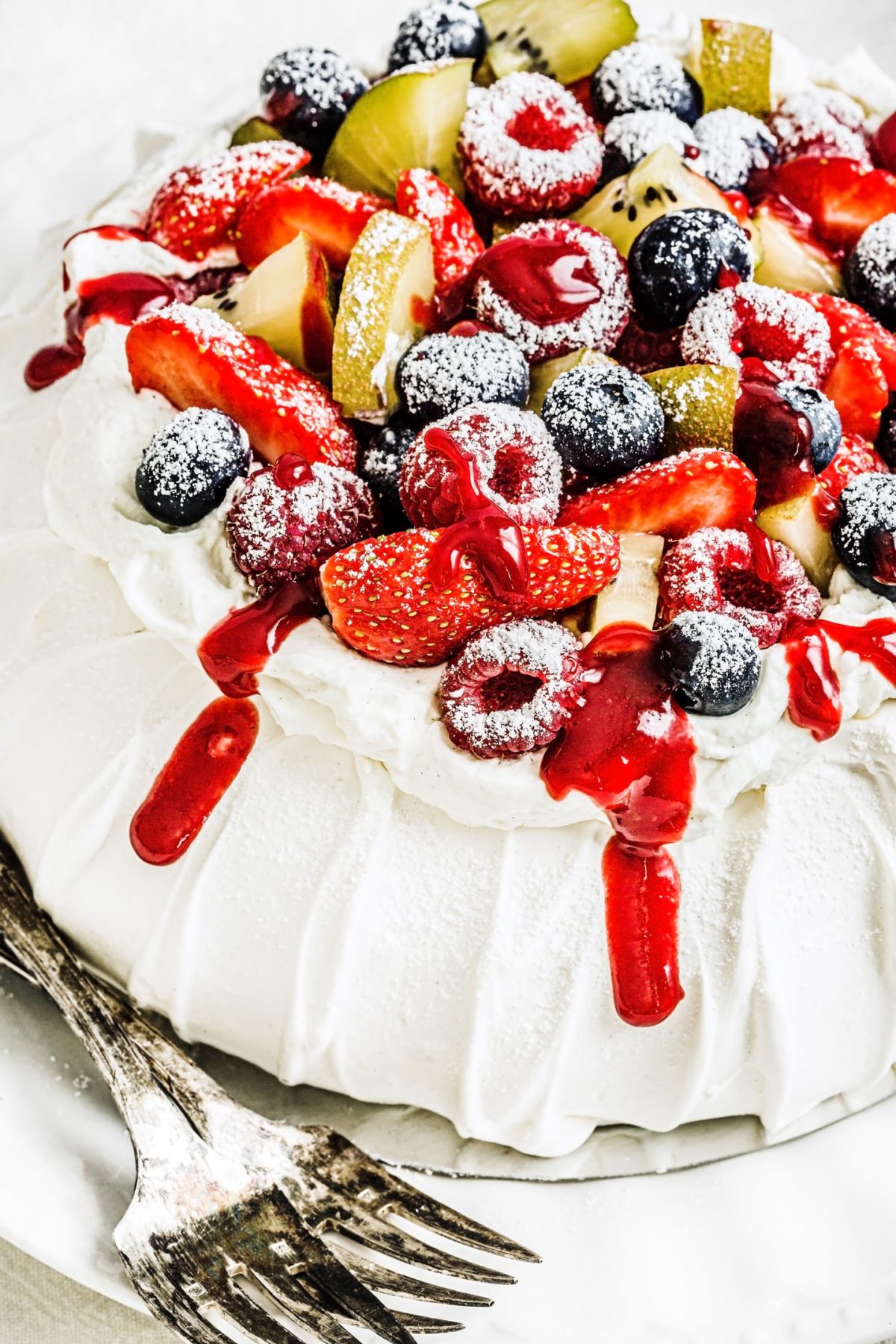 berry pavlova recipe topped with mascarpone cream and fruit coulis