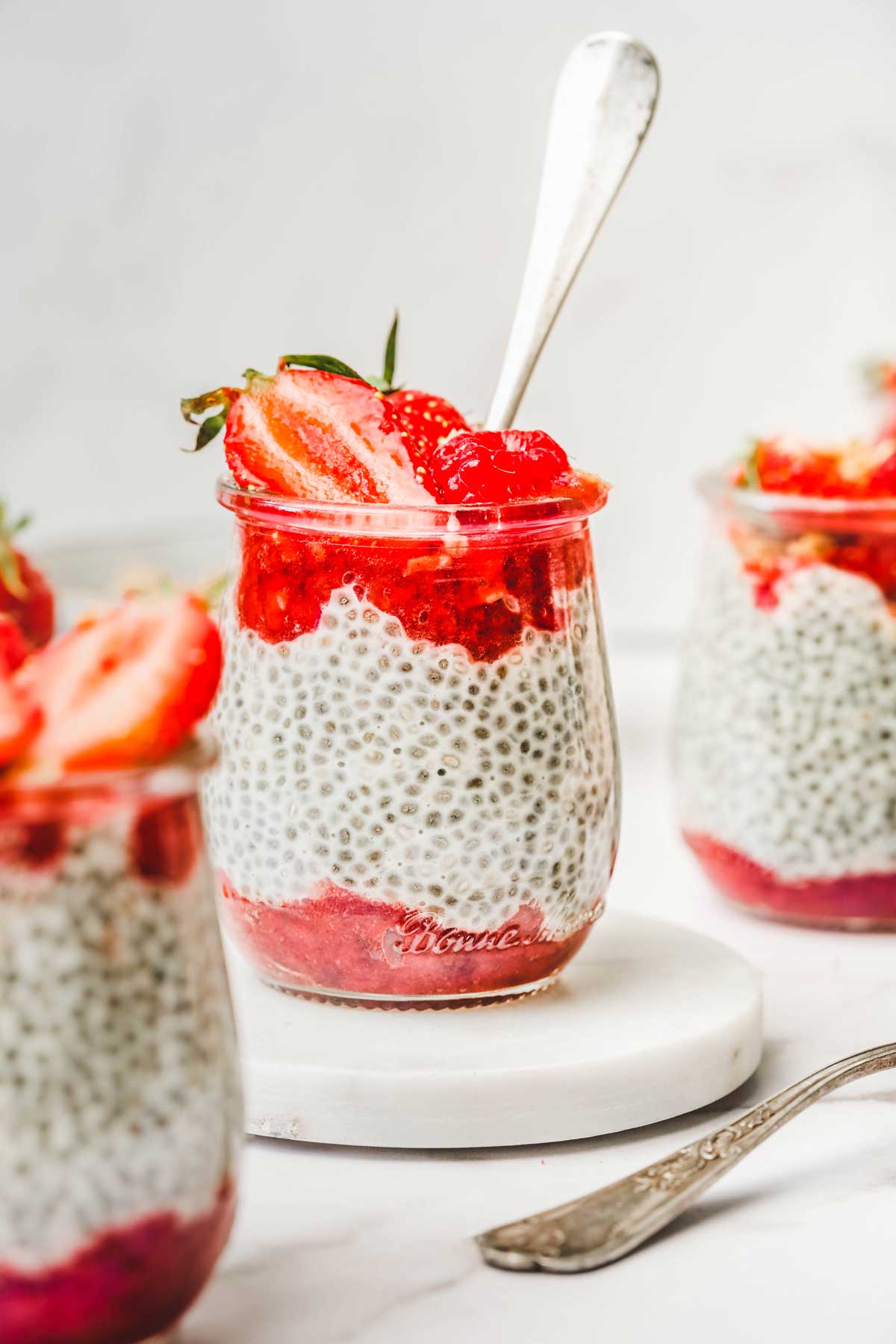 Small glass jar with strawberry puree, chia pudding and fresh fruits
