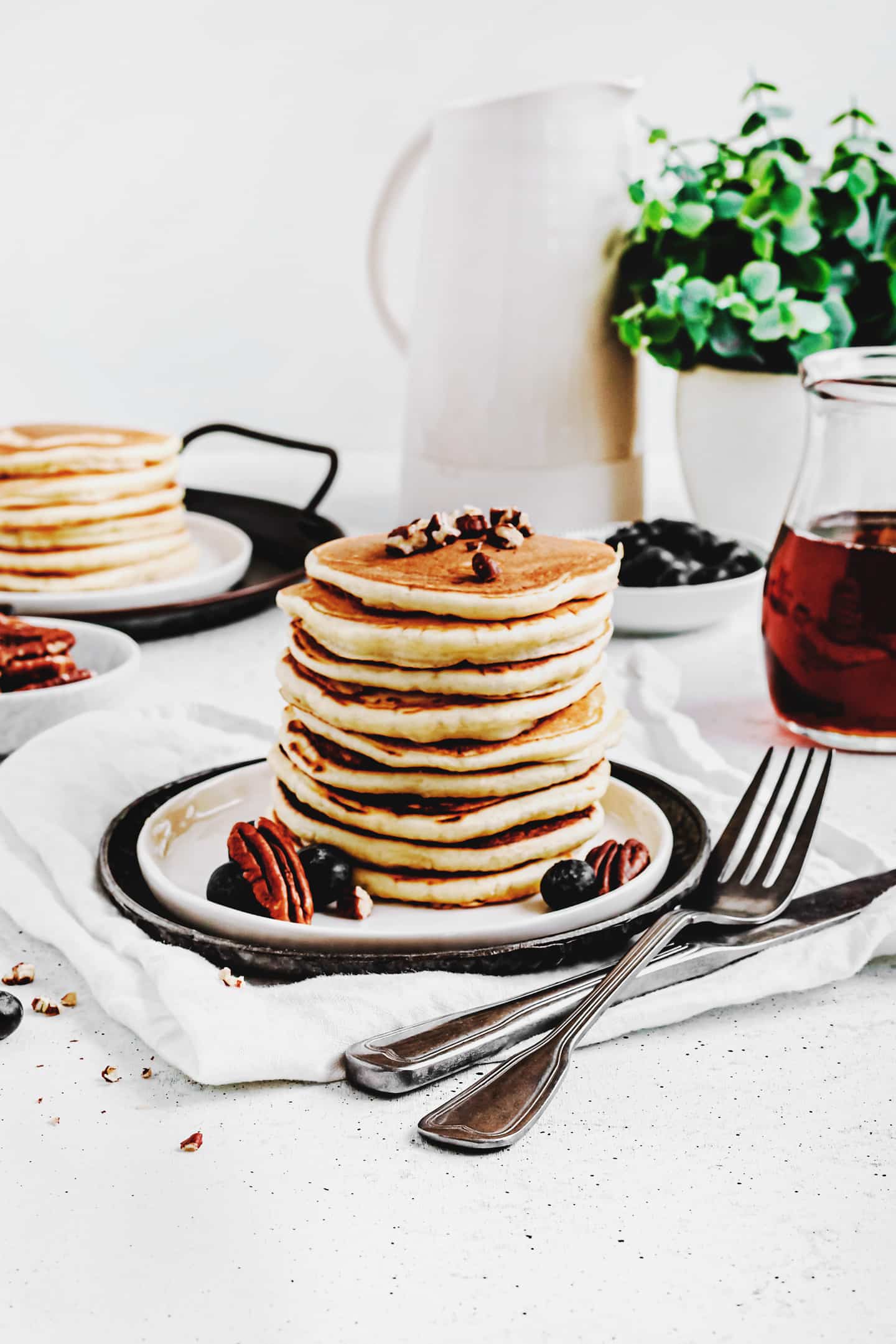 pancakes sur une table avec des myrtilles et des noix de pécan