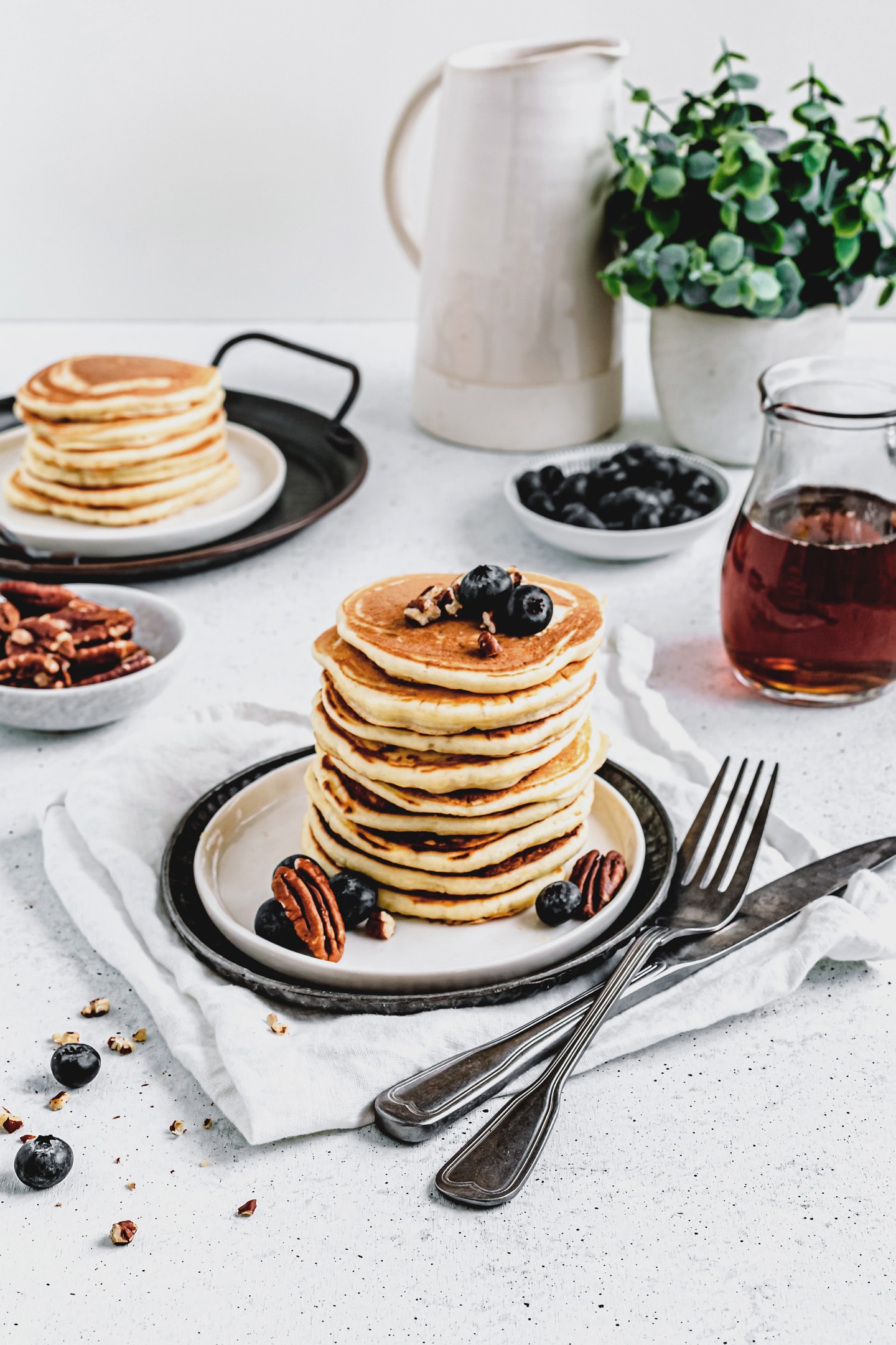 Stack of fluffy American buttermilk pancakes topped with fresh berries and a drizzle of maple syrup.