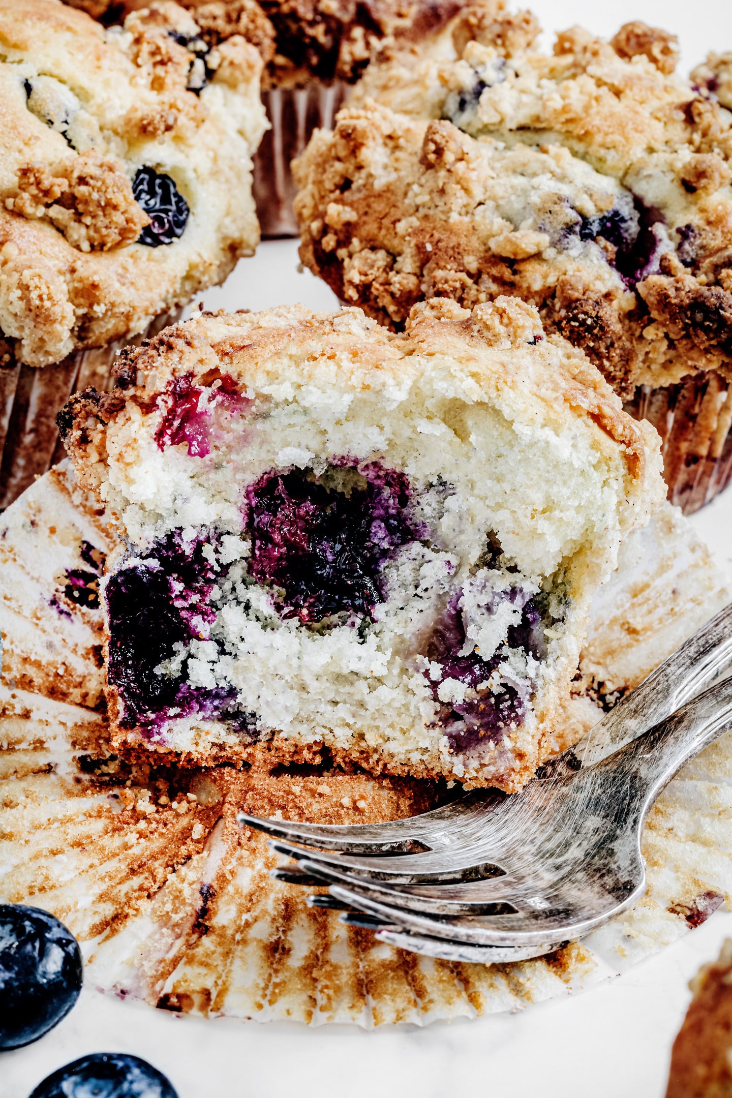 Blueberry streusel muffin cut in half with a fork