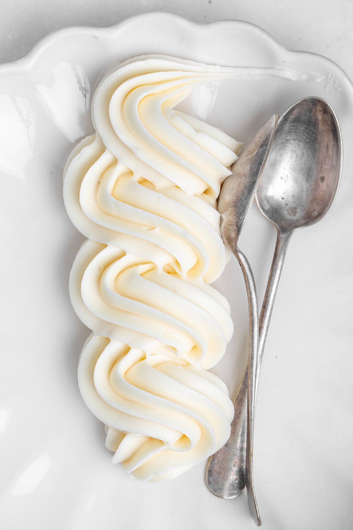 Cream cheese frosting piped onto a plate, smooth and creamy texture