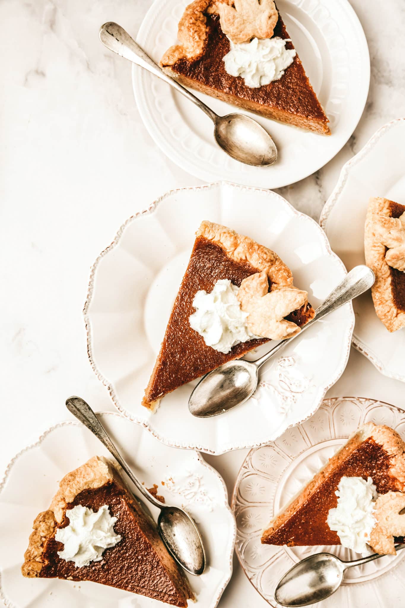 Somes dessert plates with slices of pumpkin pie with whipped cream