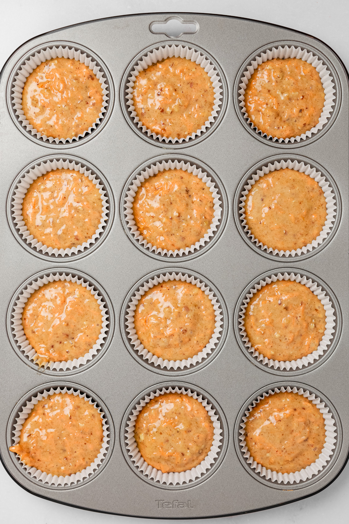 Cupcake pan filled with carrot cake cupcakes batter before baking