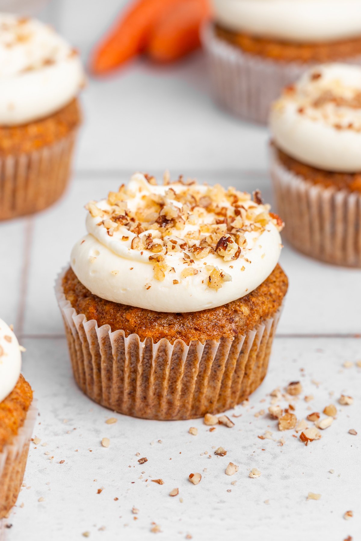 Carrot cake cupcakes on a table with cream cheese frosting