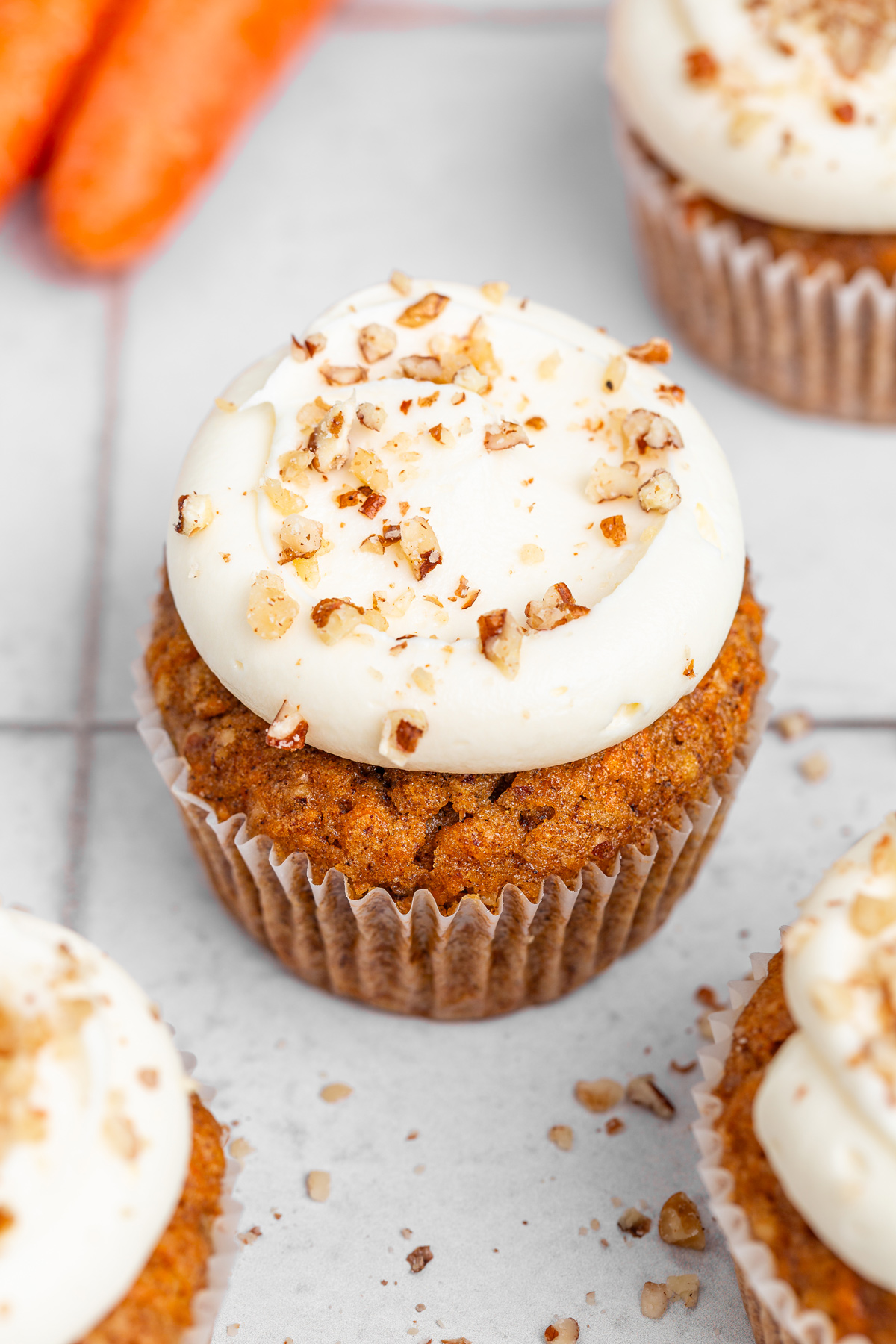 Frosted carrot cake cupcakes with chopped nuts on top