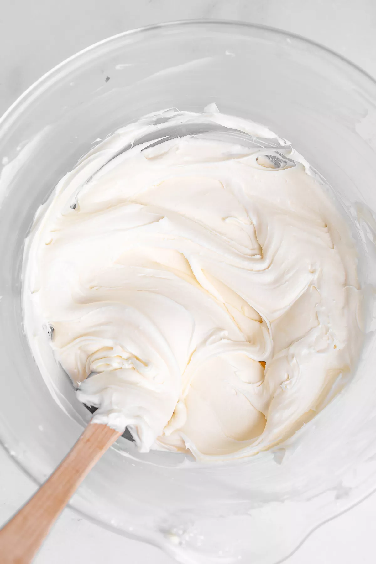 Mixing bowl with smooth cream cheese frosting for carrot cake cookies