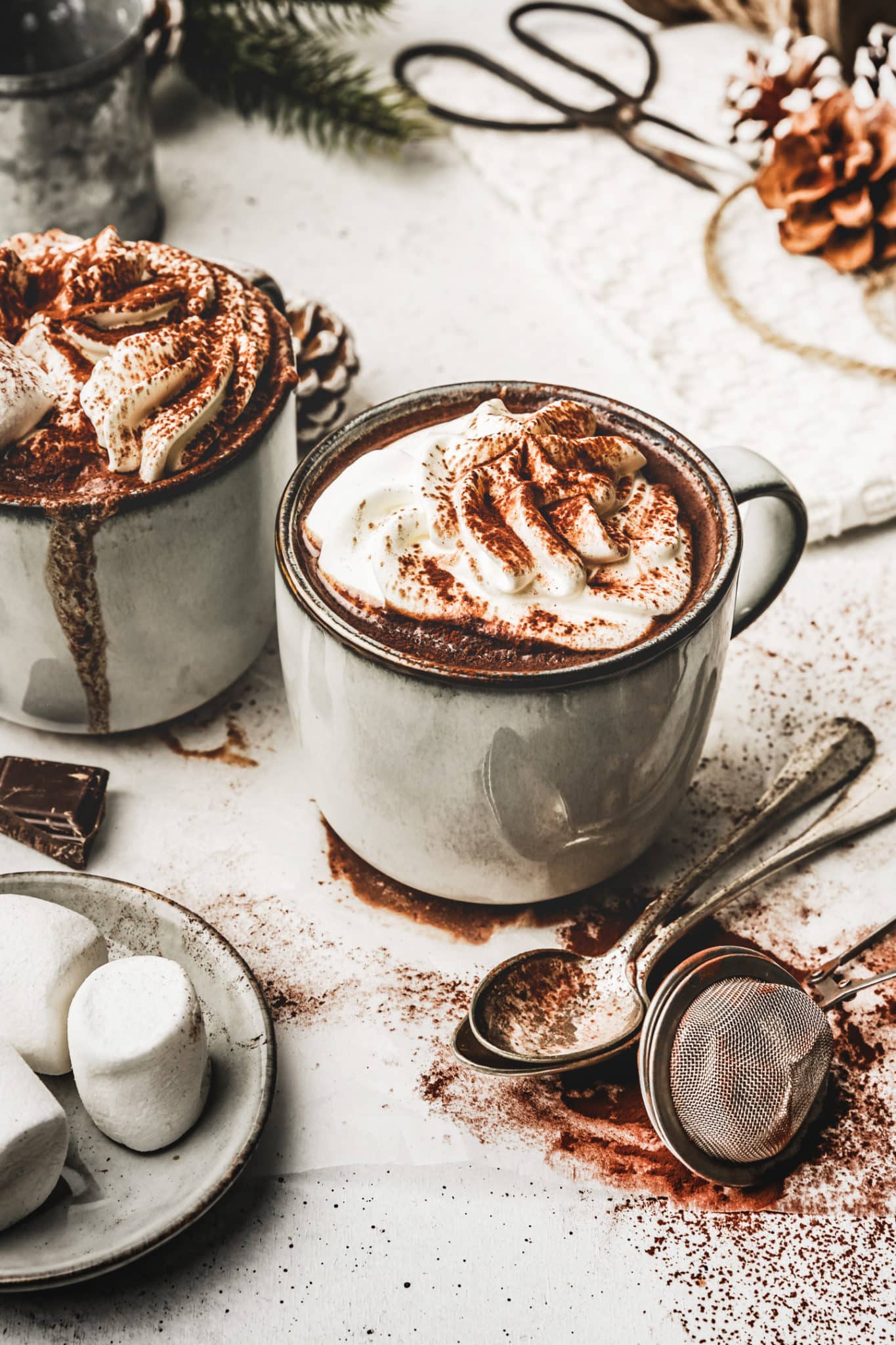 Hot chocolate cups with teaspoons and marshmallows on a christmas table