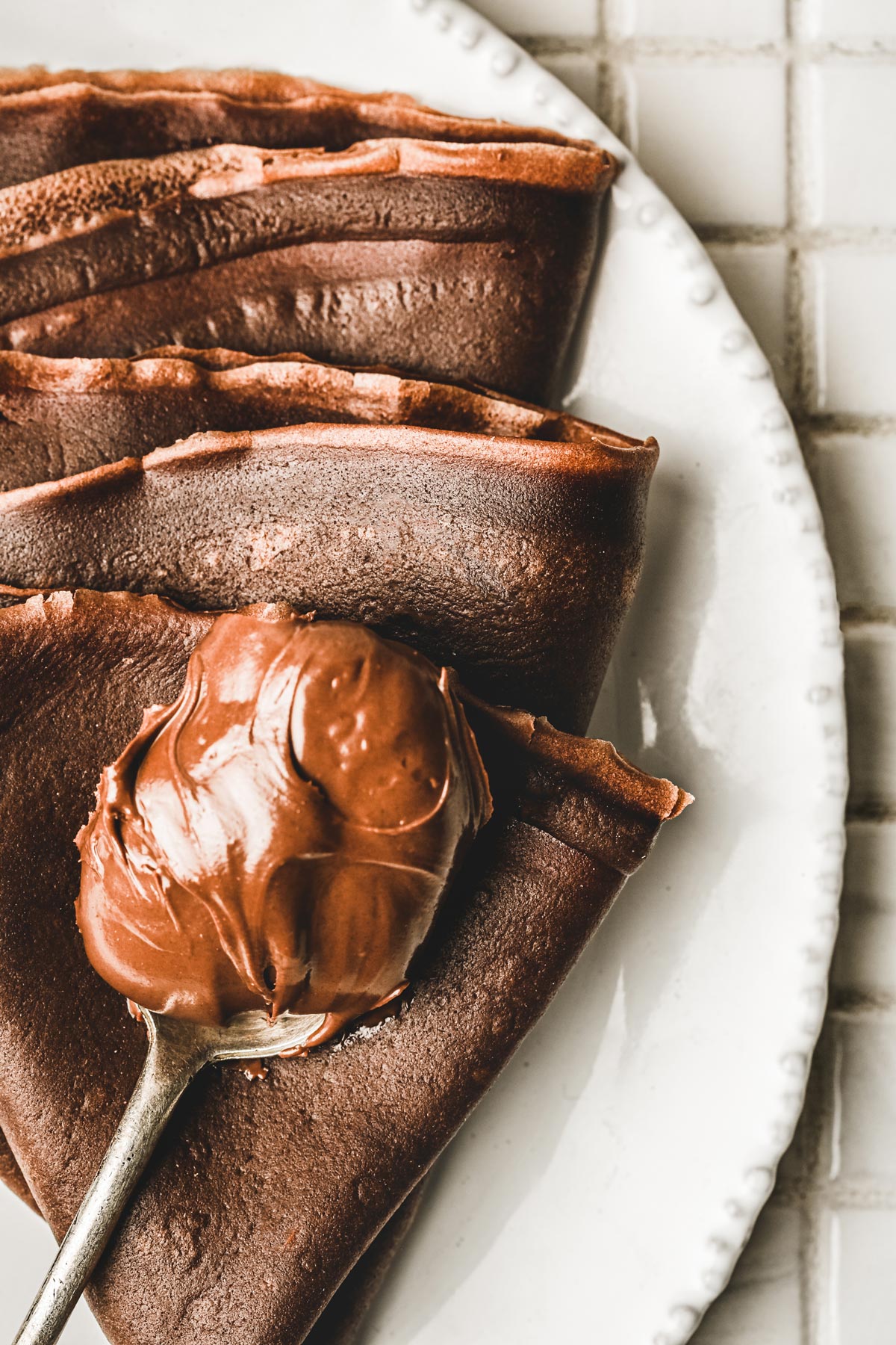 Assiette avec des crêpes au chocolat et une cuillère de nutella