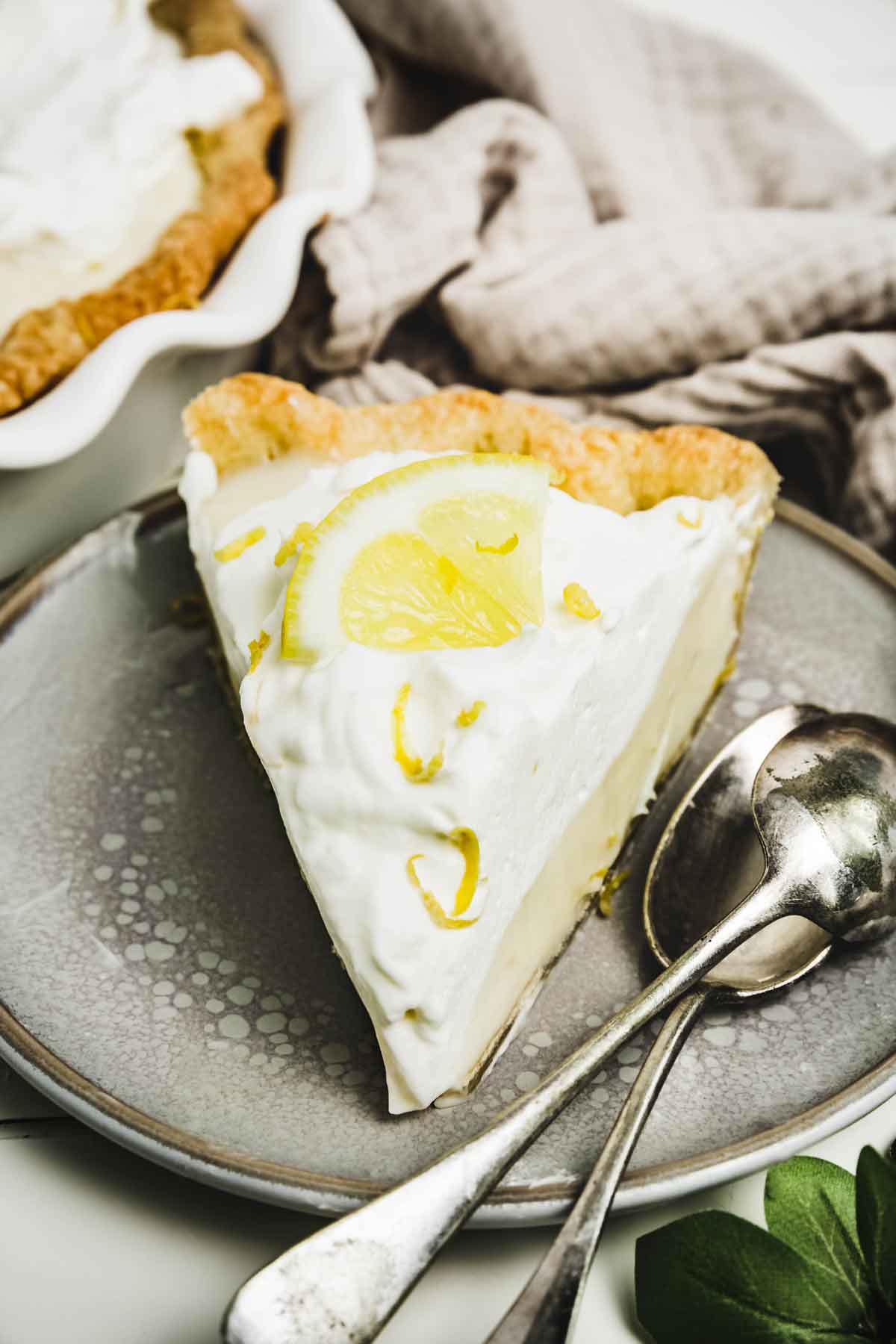 Part de tarte au citron dans une assiette avec des petites cuillères