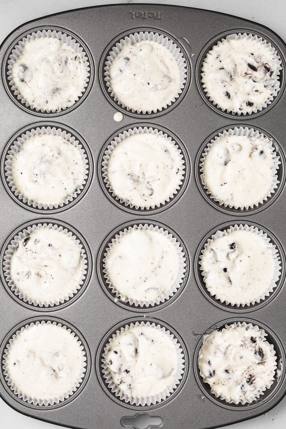 muffin pan filled with mini oreo cheesecakes before baking