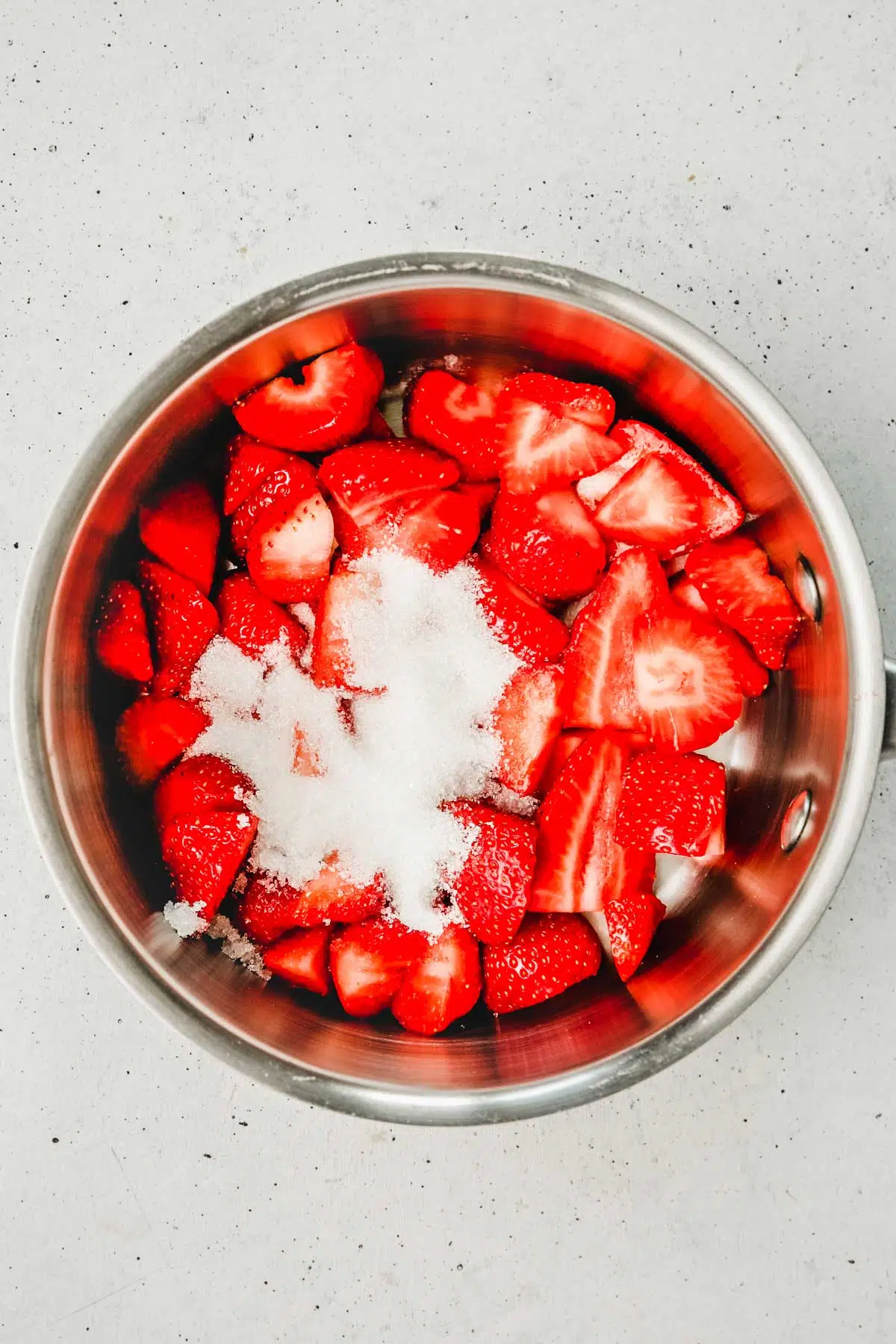 Casserole avec des morceaux de fraises et du sucre en poudre
