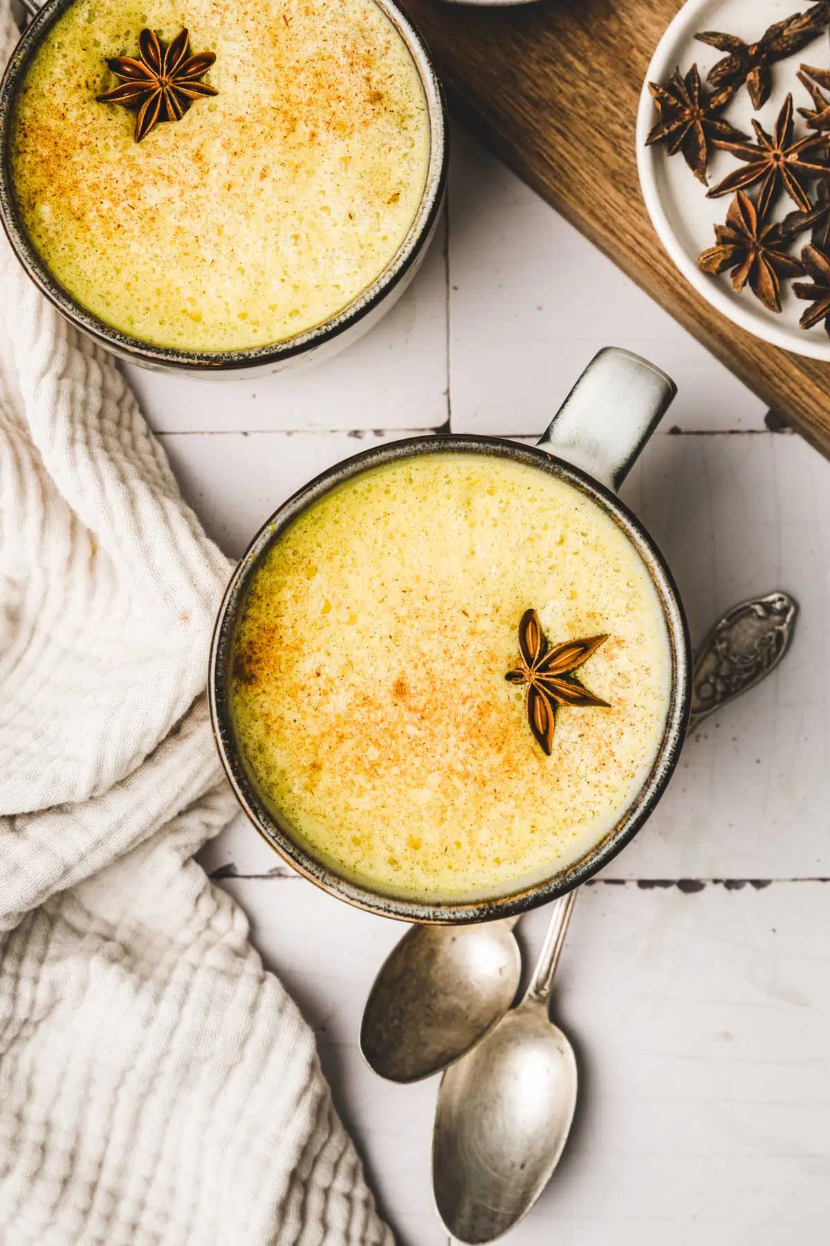 Cup with turmeric milk, star anise and teaspoons