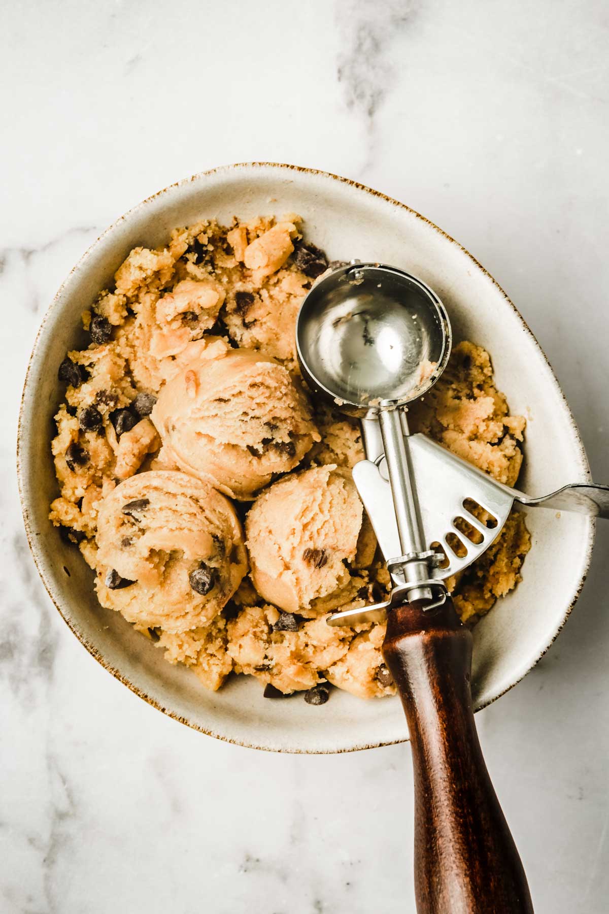 Bowl with ice cream scoop and cookie dough