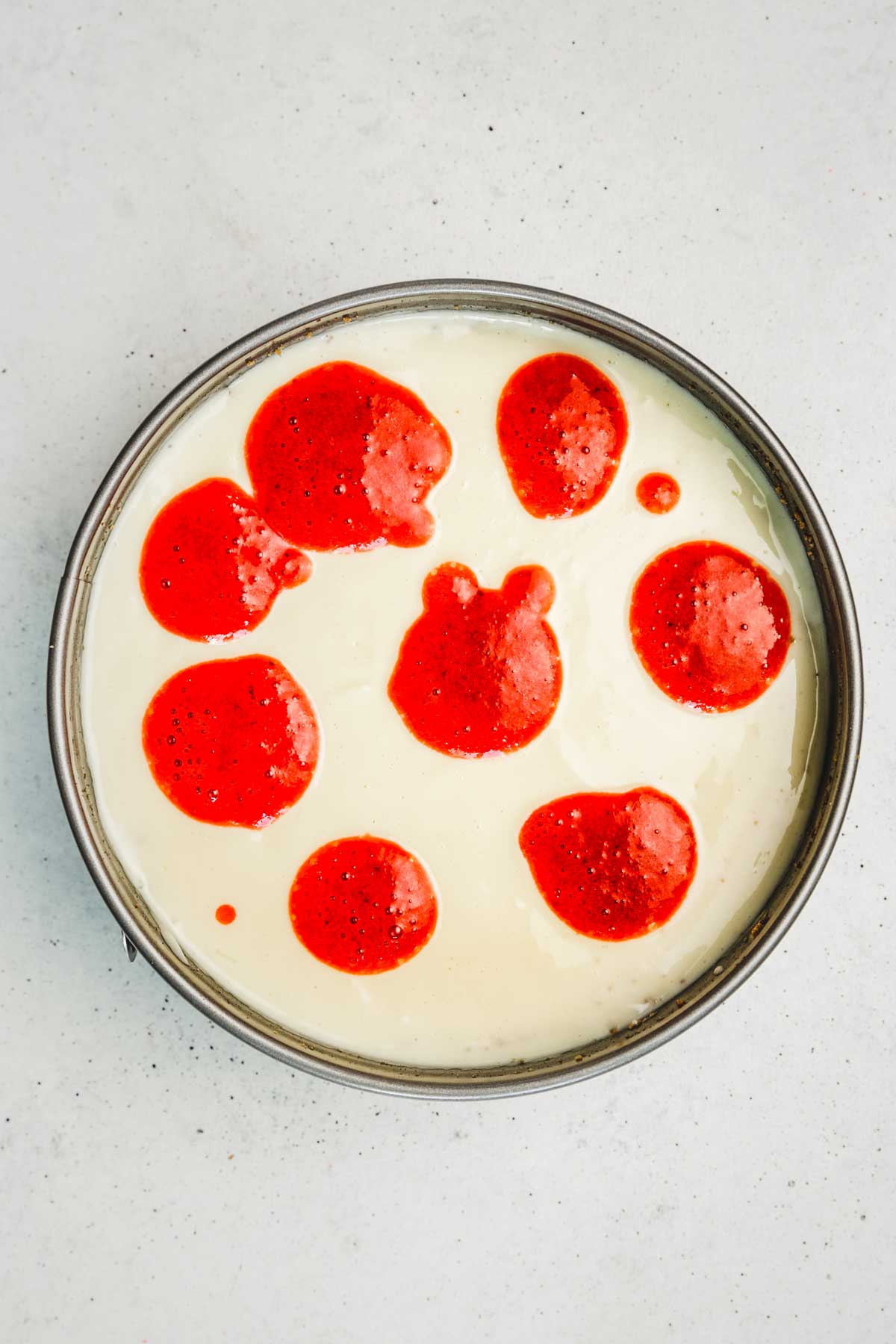 Springform pan with strawberry batter with strawberries dot