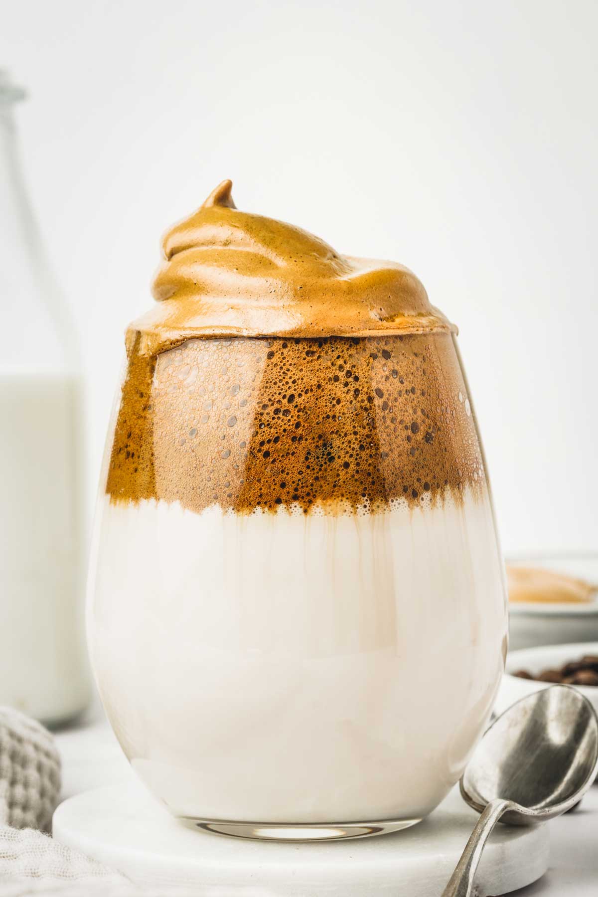 Large glass of milk with whipped coffee foam and a teaspoon