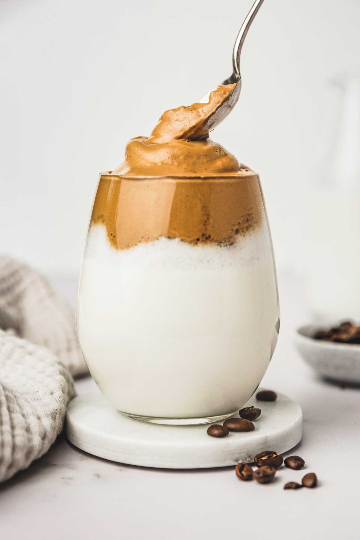 Glass with milk and whipped coffee foam and a teaspoon