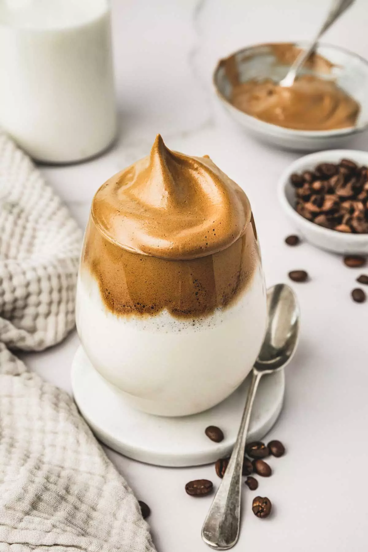 Glass of milk with whipped coffee foam and a teaspoon