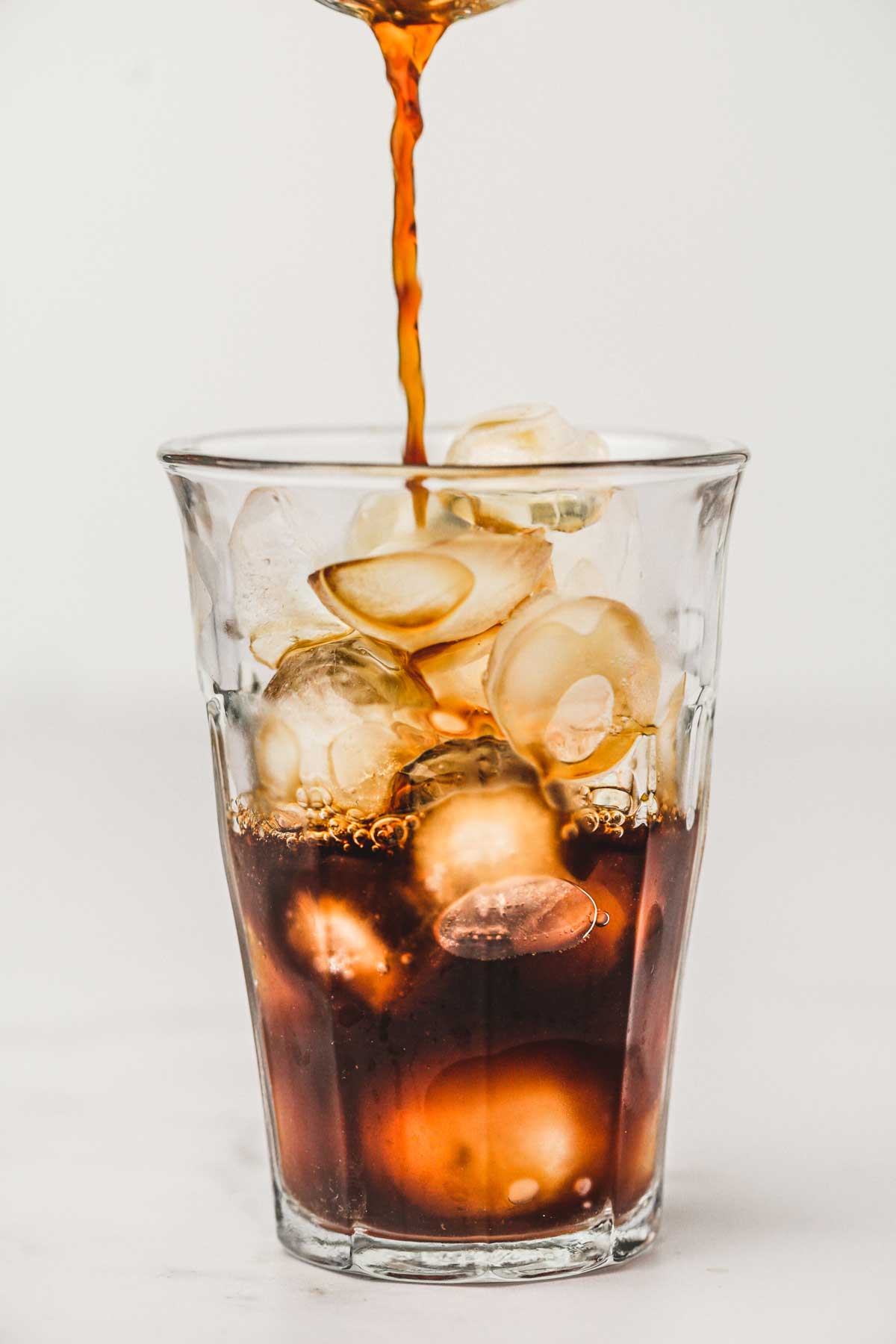 Café noir qui coule dans un verre rempli de glaçons