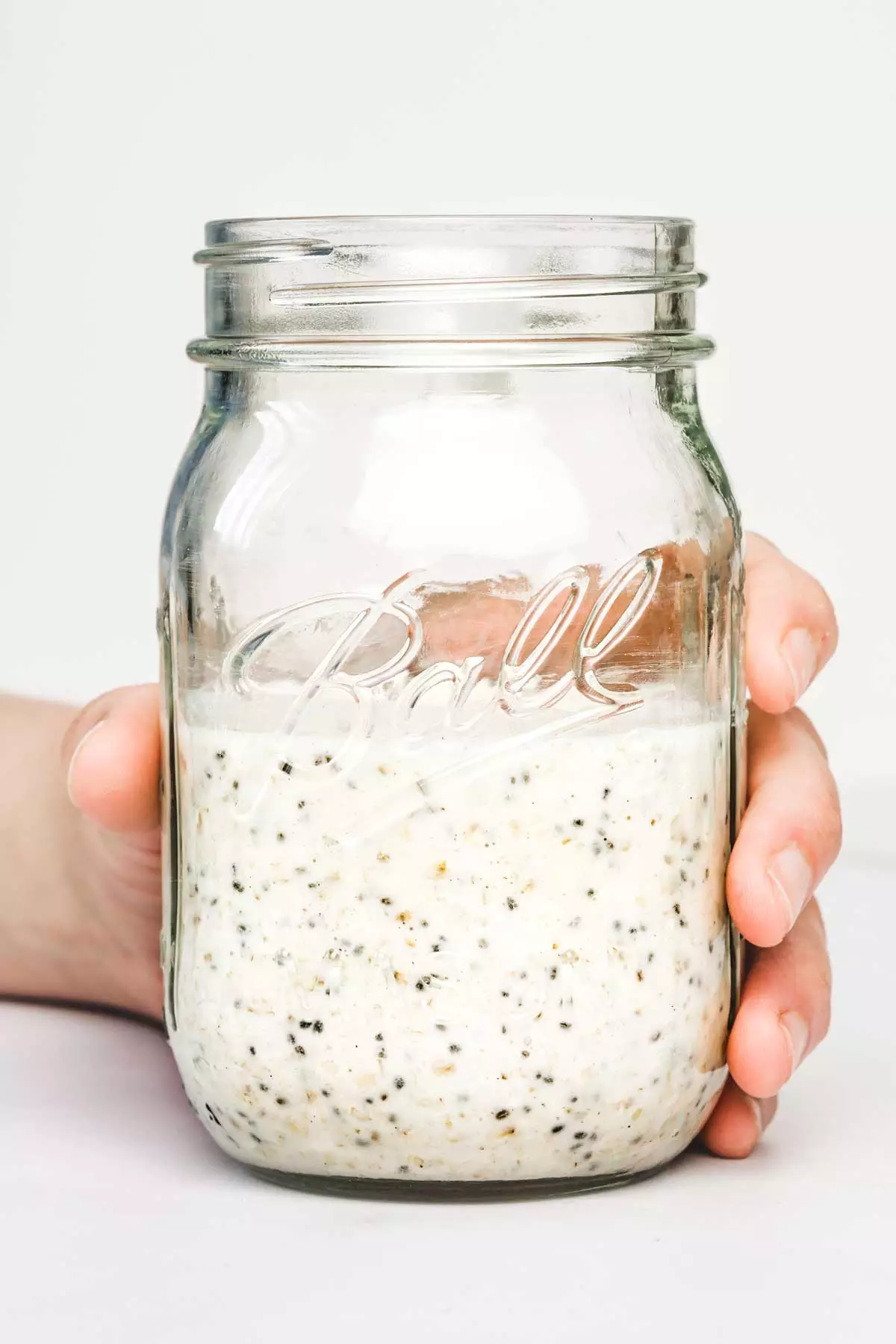 Main qui tien un bocal avec des flocons d'avoine du lendemain