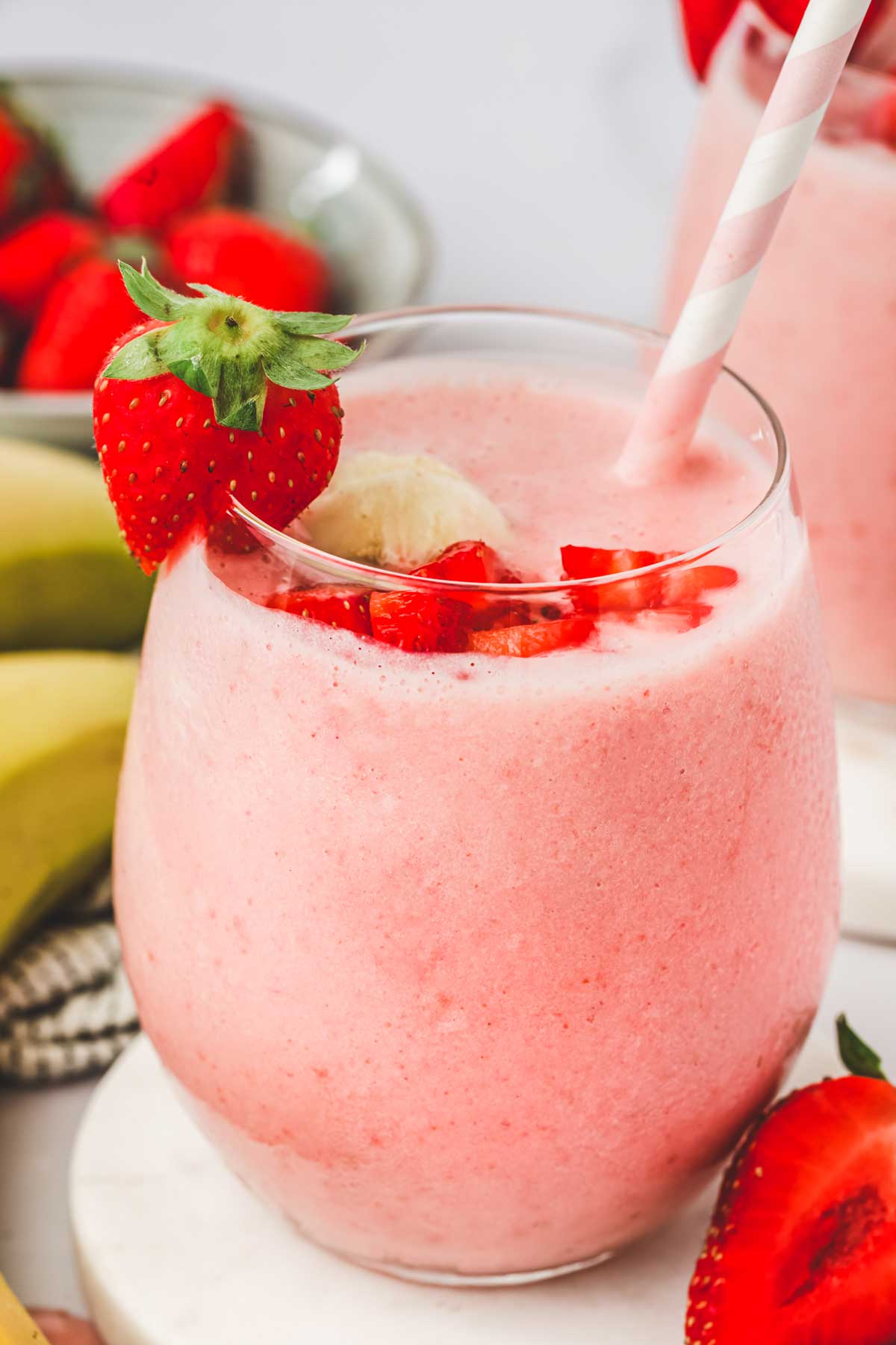 Verre de smoothie fraise banane avec des fraises en morceaux et des bananes