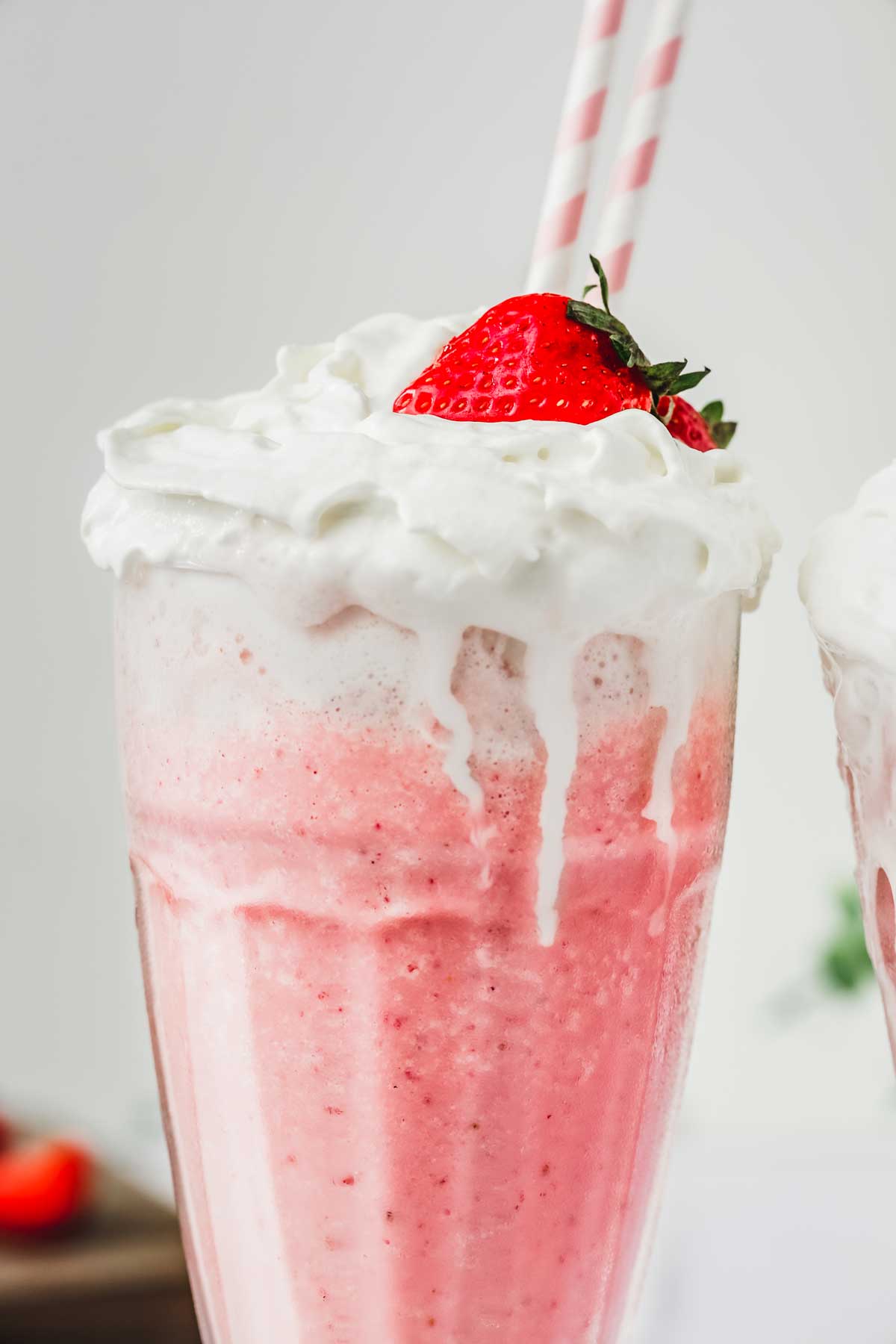 Strawberry in a strawberry milkshake with a straw