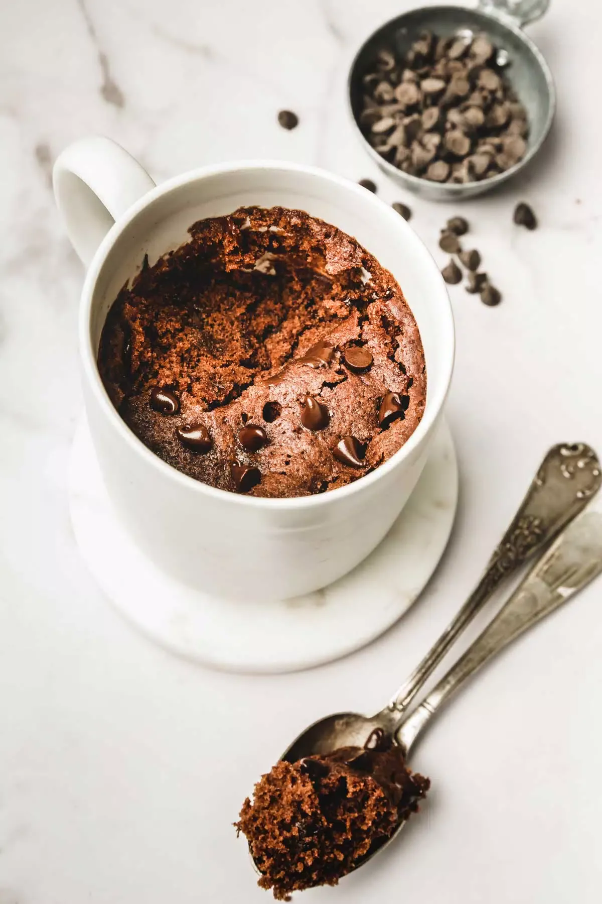 Un mug avec du gâteau au chocolat et des cuillères à café