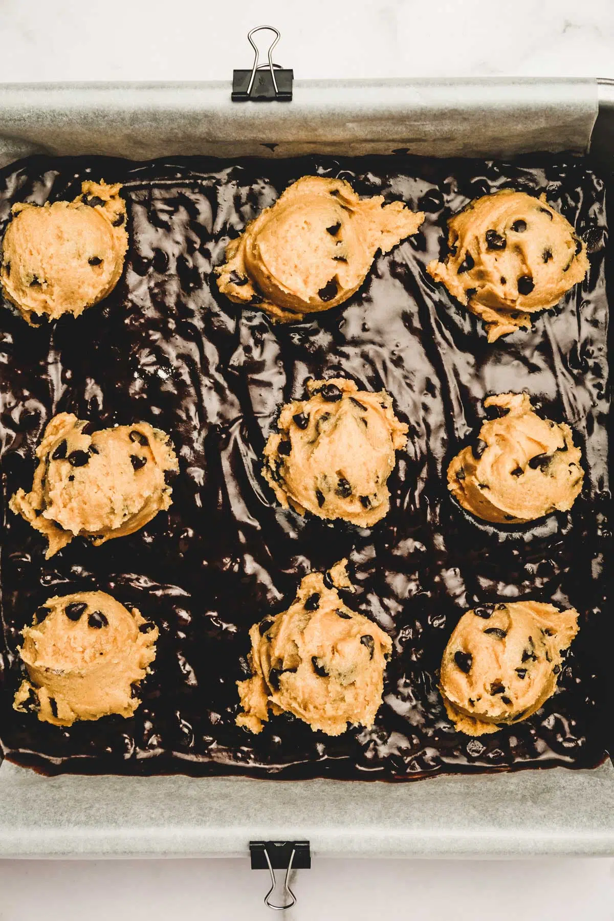 Moule carré avec pâte à brownies et boules de pâte à cookies