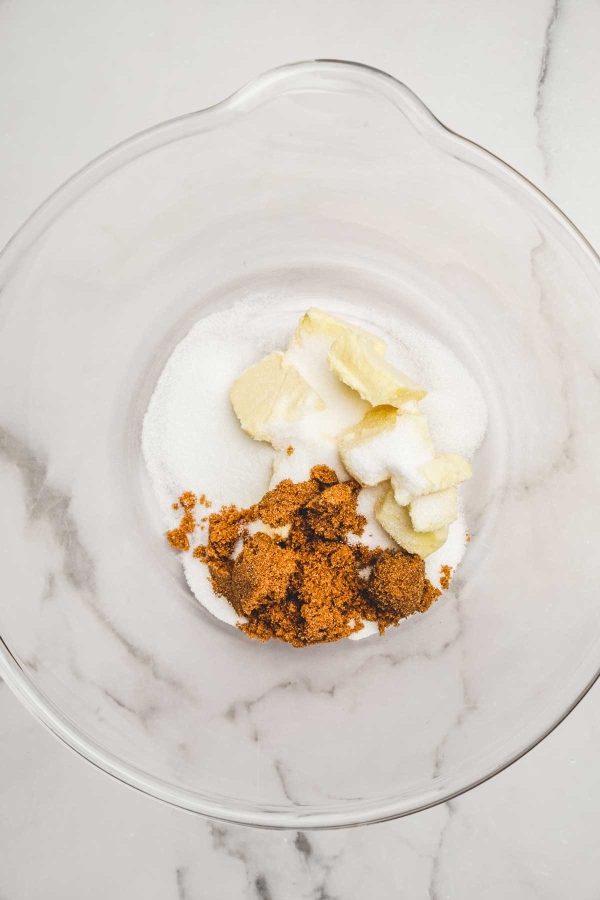 Grand bol avec du sucre en poudre, du sucre brun et des morceaux de beurre