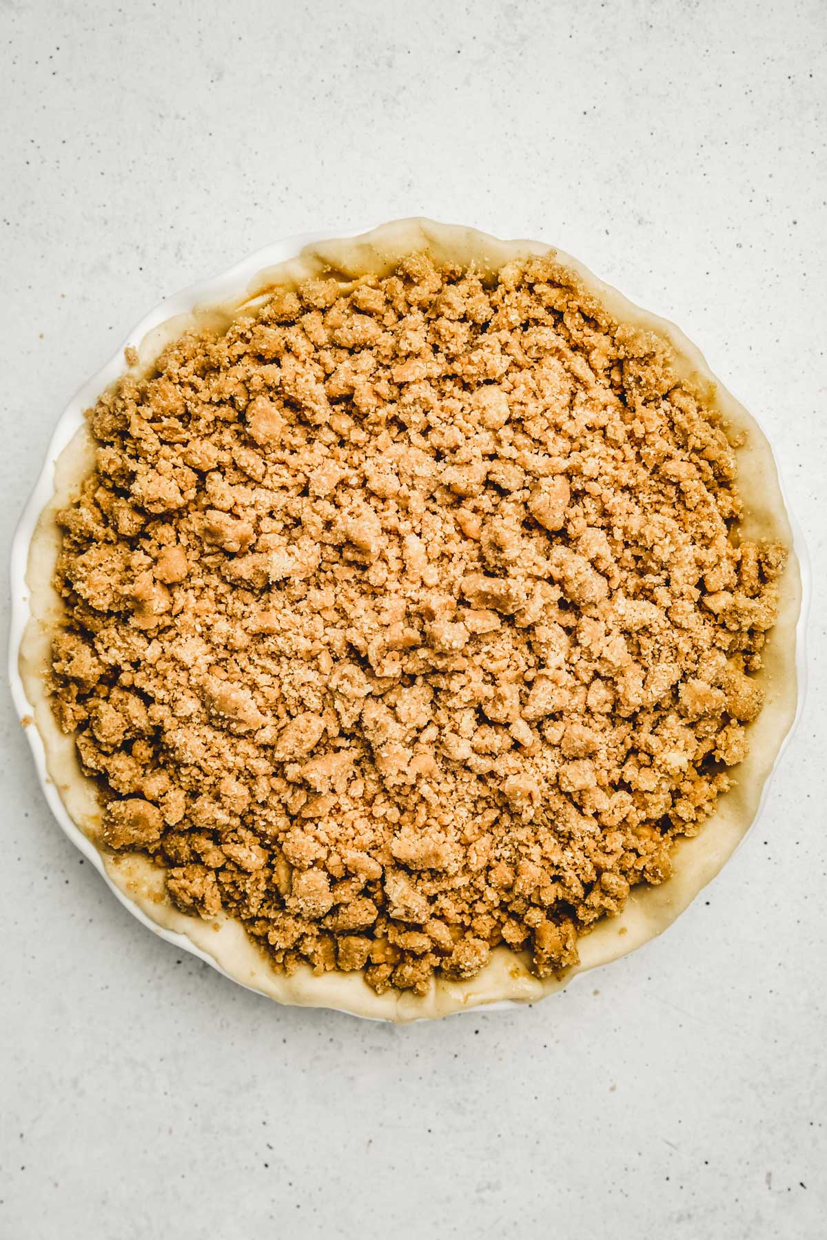 Pie plate with apple pie crumble before baking