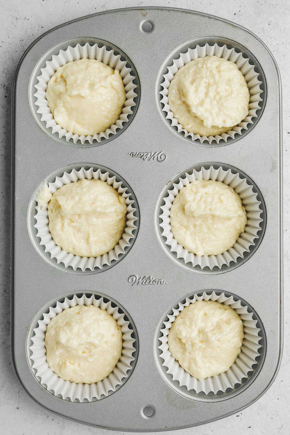 cupcake pan with coconut cupcake batter before baking