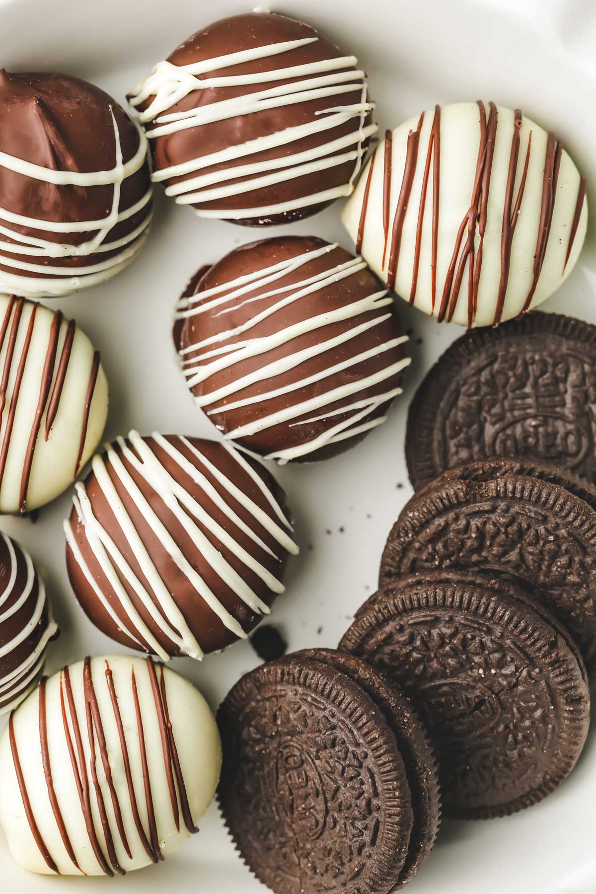  Oreo truffles on a serving plate with chocolate drizzle