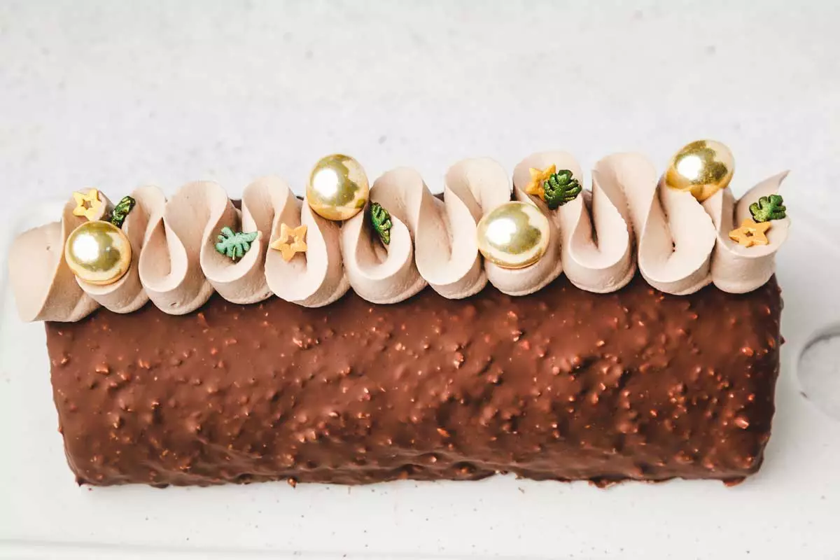 Buche au chocolat roulée avec ganache montée au lait et glaçage rocher sur un plat