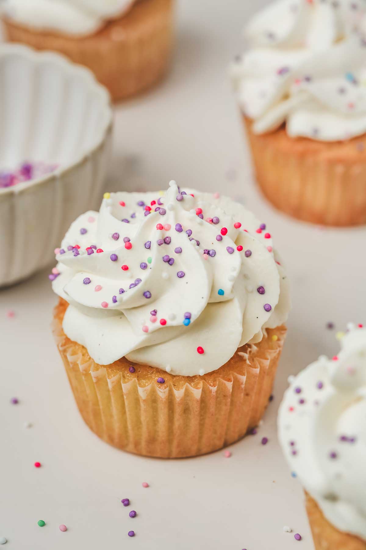Vanilla cupcakes on a table with vanilla frosting