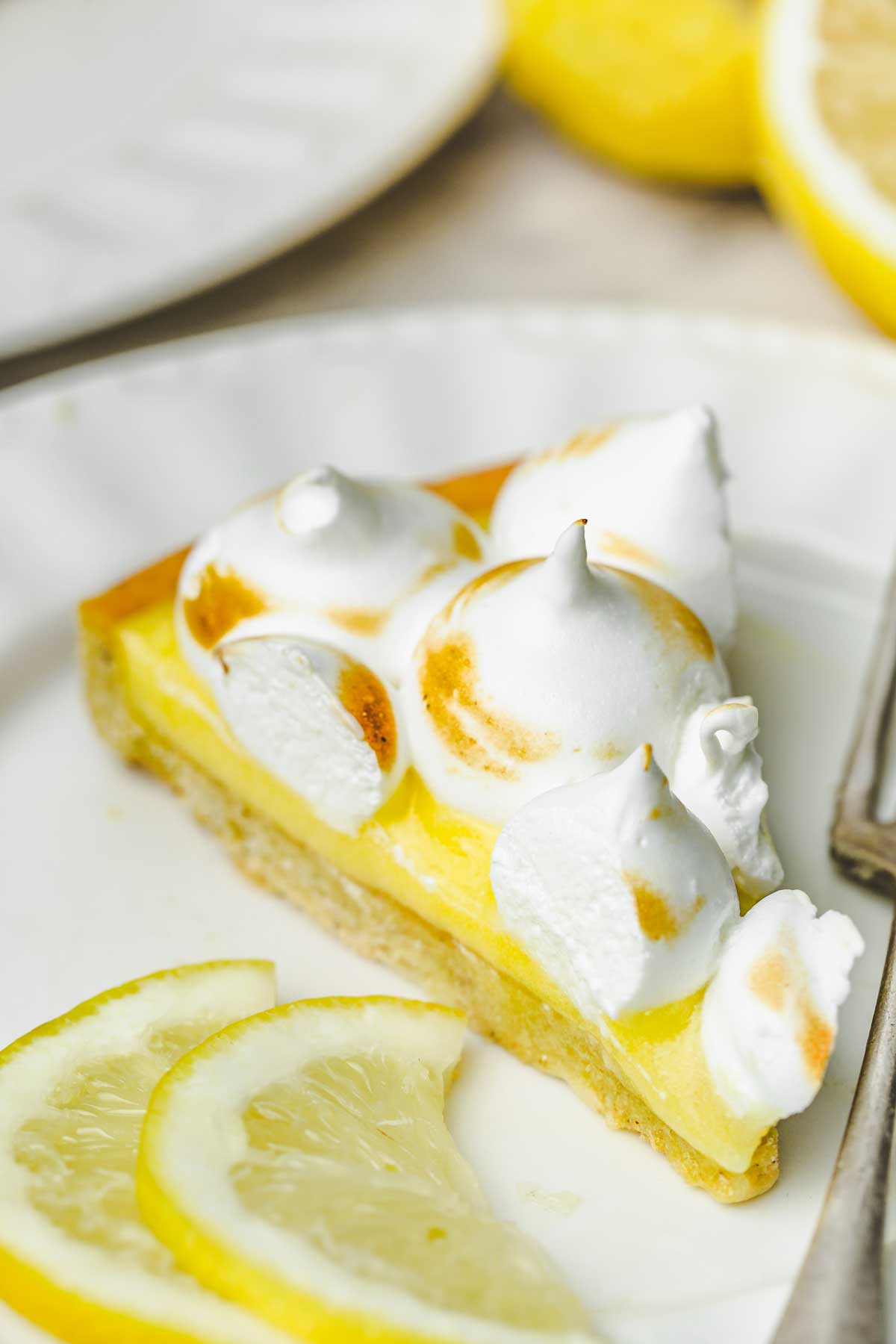 part de tarte au citron meringuée sur une table avec une fourchette