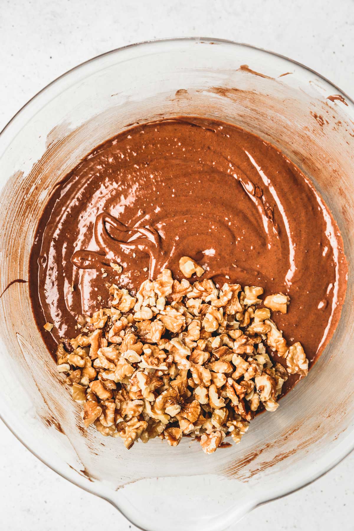 large bowl with chocolate brownies batter an chopped walnut