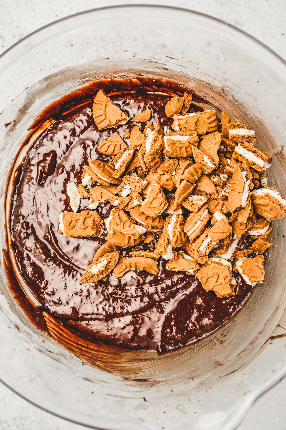 large mixing bowl with brownies batter and crushed biscoff cookies