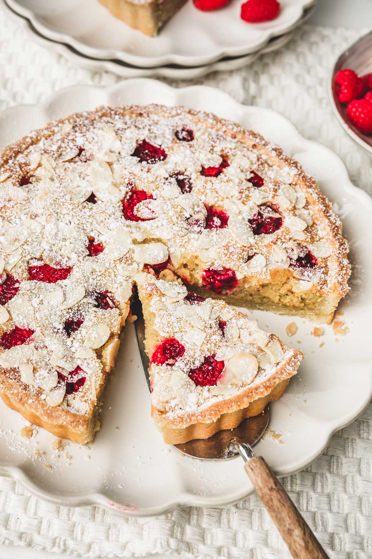 sliced raspberry frangipane tart on a plate