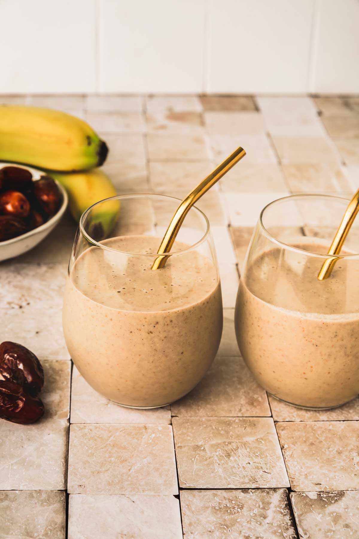 two glasses of banana dates smoothie on a table
