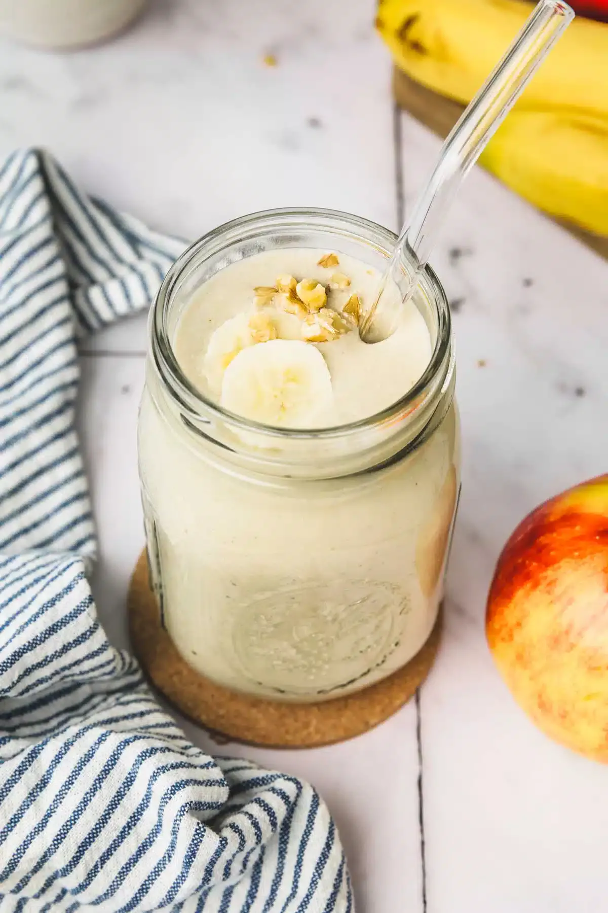 glass jar with apple banana smoothie on a table