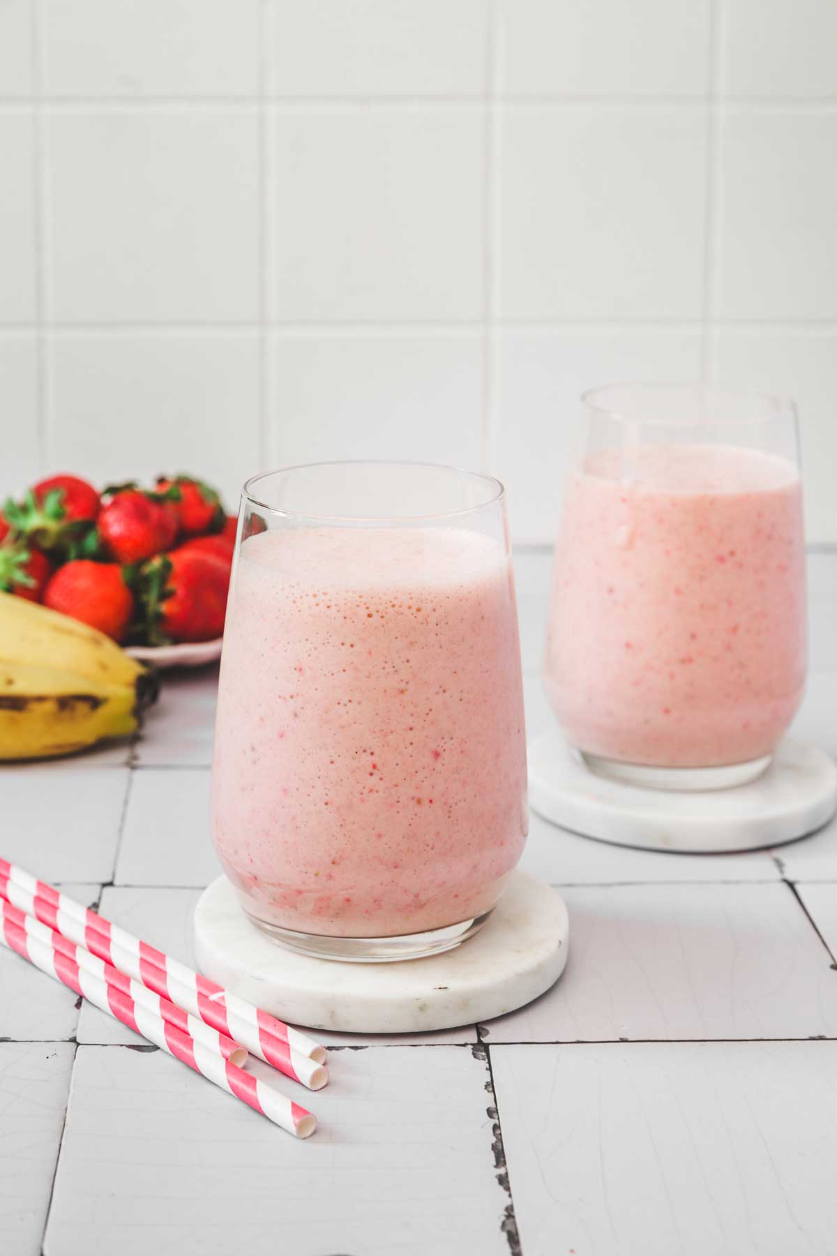 two glasses with strawberry banana milkshake