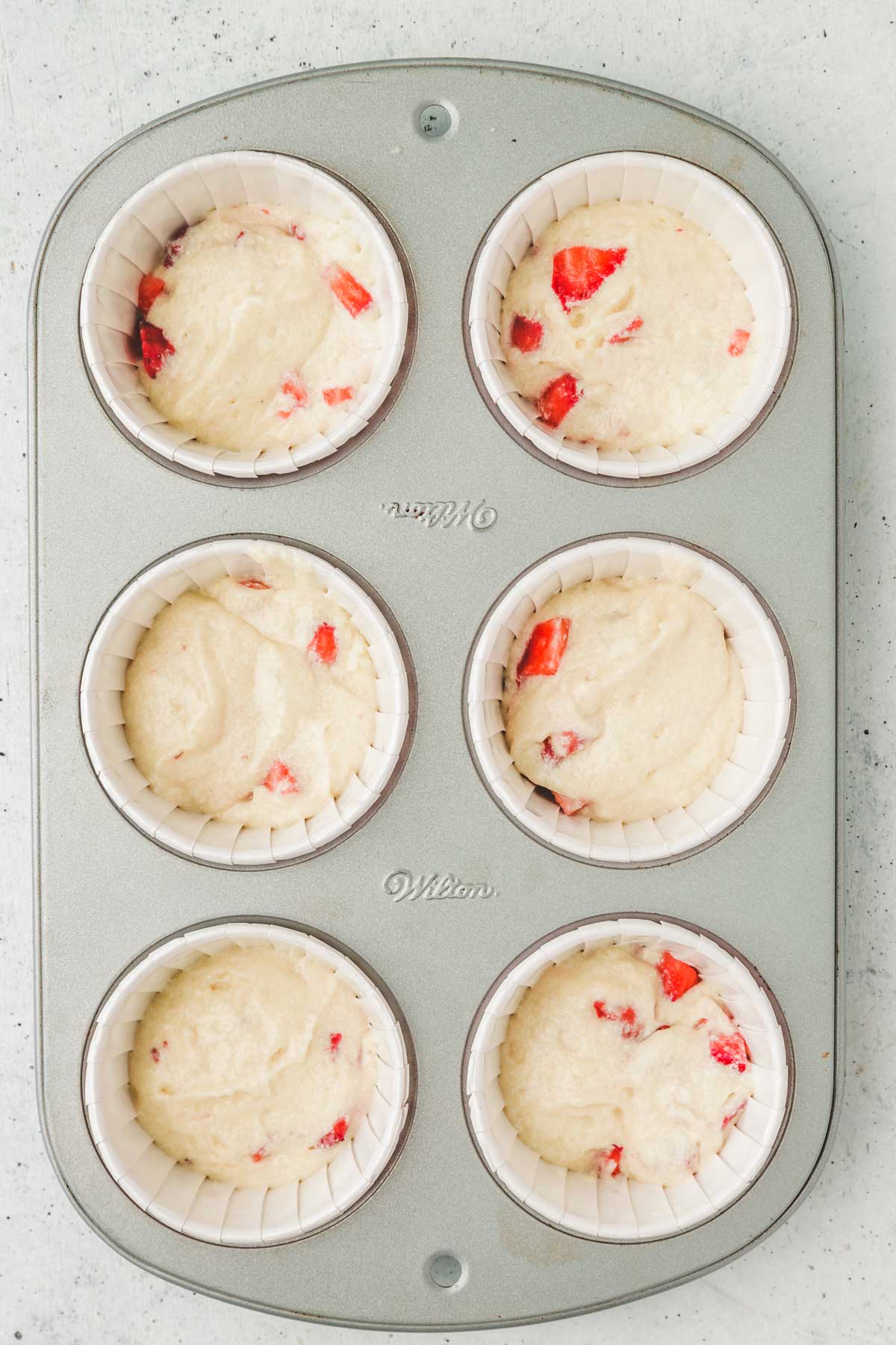 muffin pans with strawberry cupcakes batter