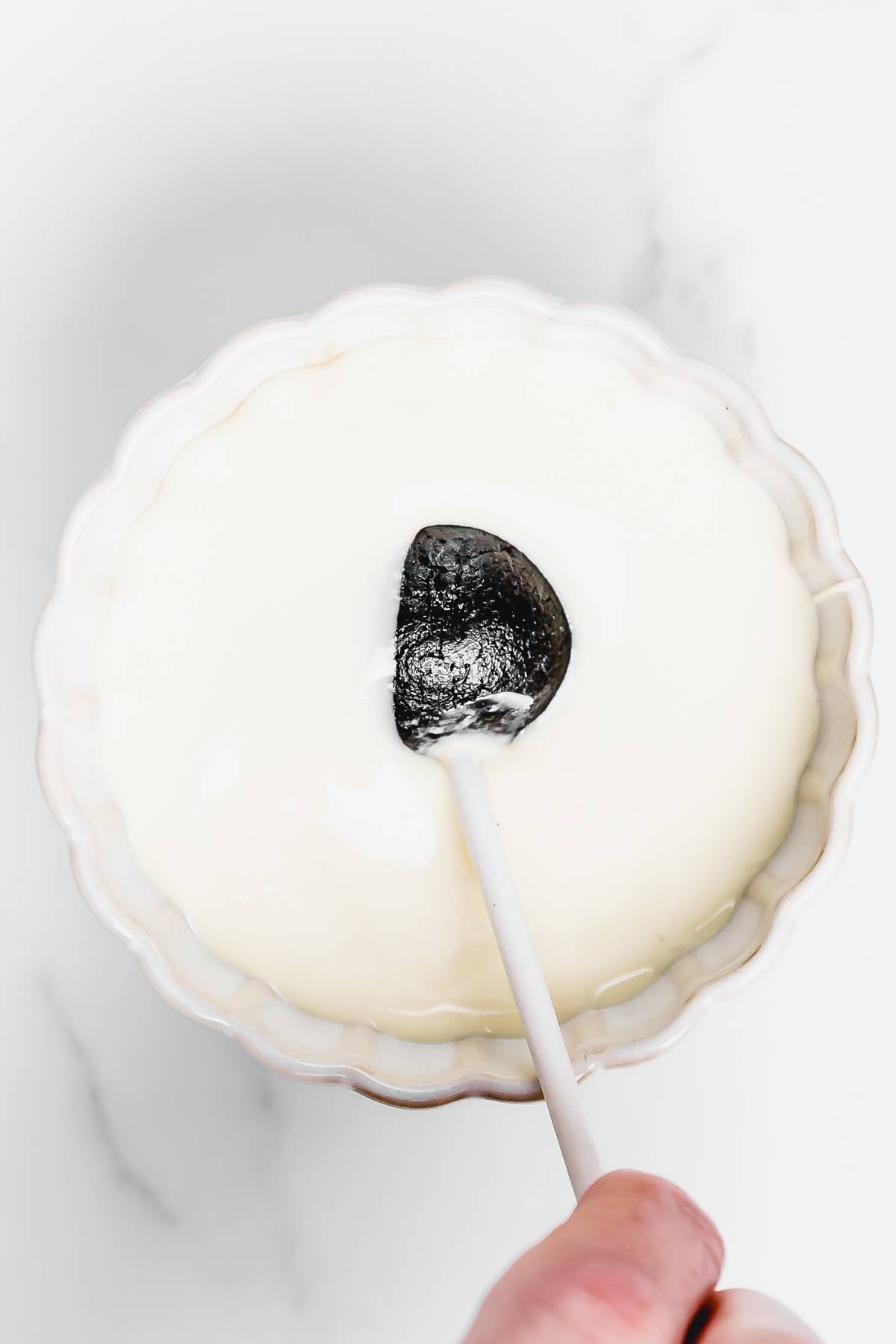 Dipping an Oreo cake pop into a bowl of melted white chocolate for coating, step-by-step no-bake Oreo cake pops recipe.