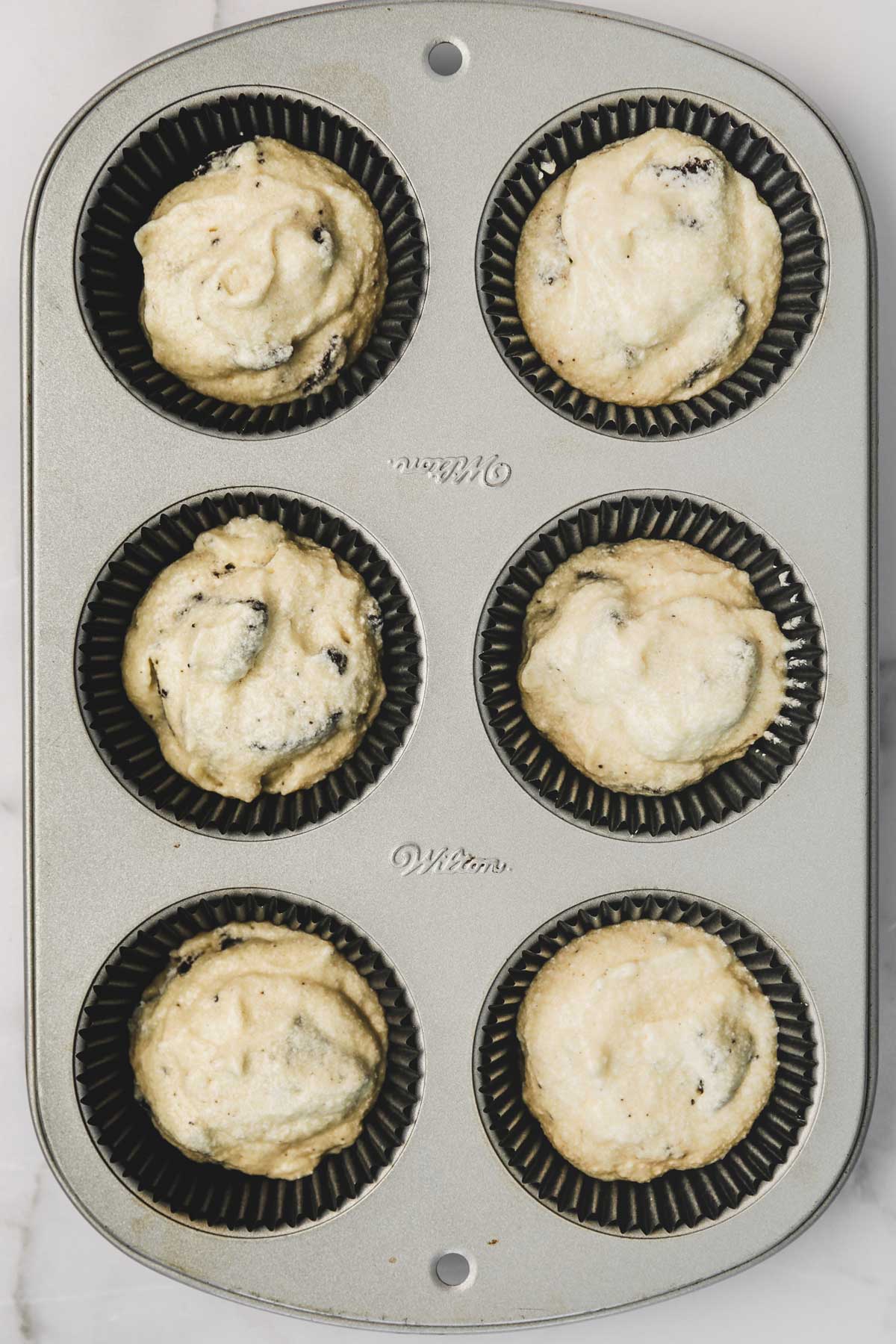 oreo cupcake batter in lined cupcake pan before baking