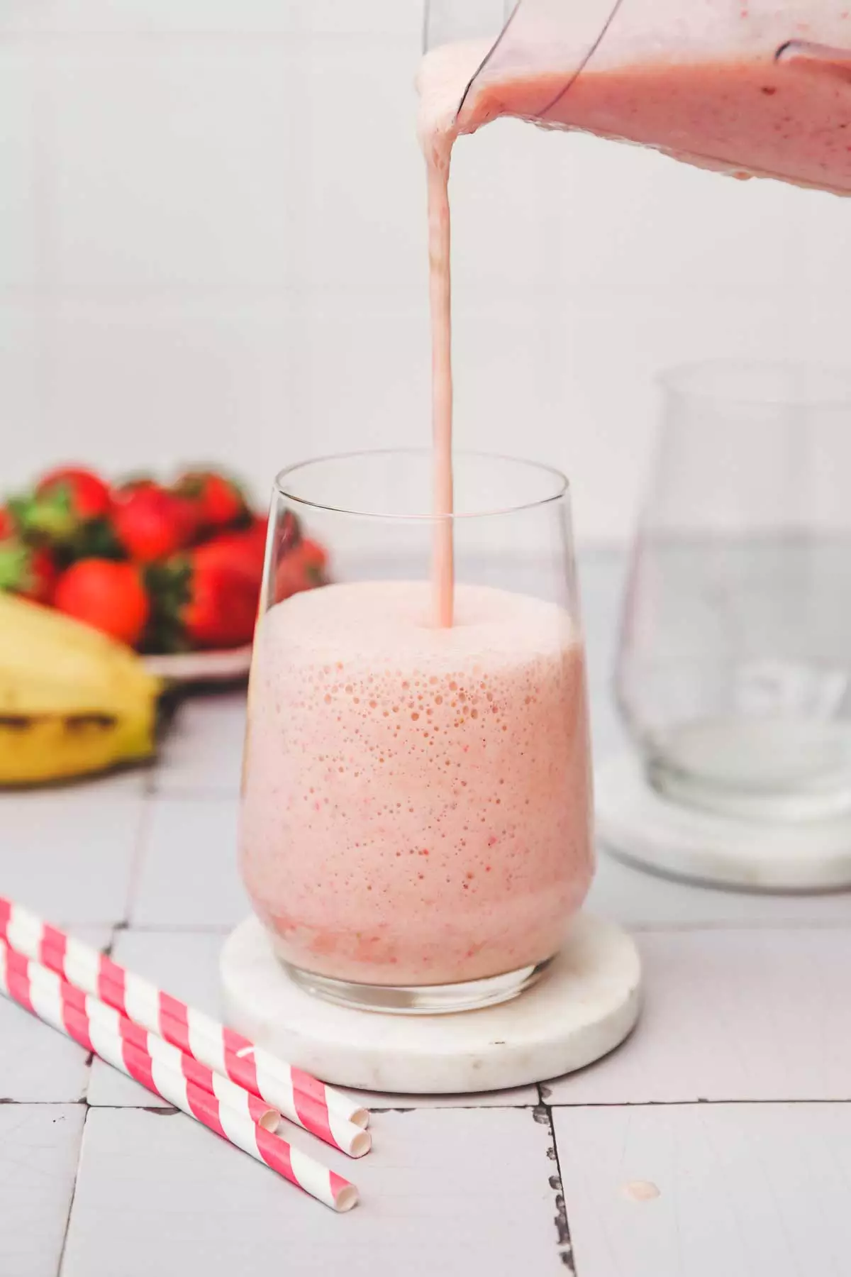 strawberry banana milkshake mixture poured on a glass